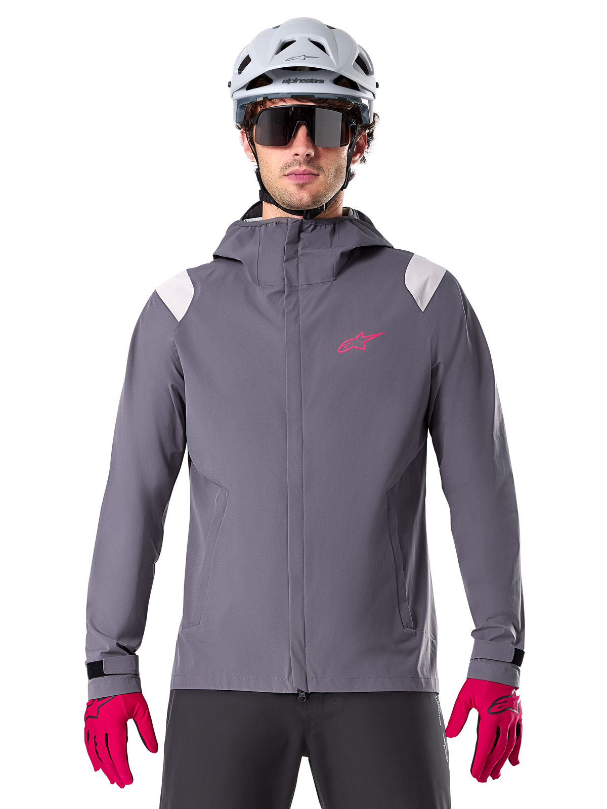 Alpinestars A-Dura Rain Jacket, Mountain Bike Rain Jacket, Dark Titanium Gray, hooded design with pink Alpinestars logo and light gray shoulder panels, worn with white MTB helmet and bright pink gloves, waterproof gear for off-road cycling