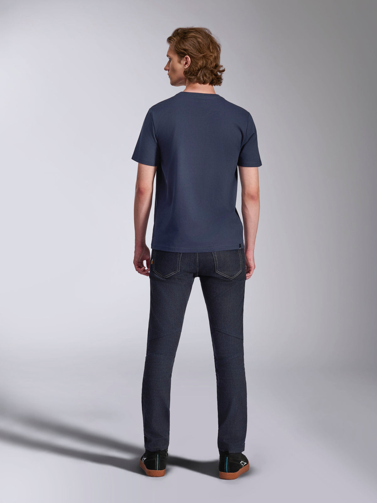 Alpinestars Ageless 2.0 CSF Tee, kortærmet t-shirt, navy, set bagfra, båret af en mand med mørke denimjeans og sorte sneakers, afslappet motorsport-inspireret streetwear
