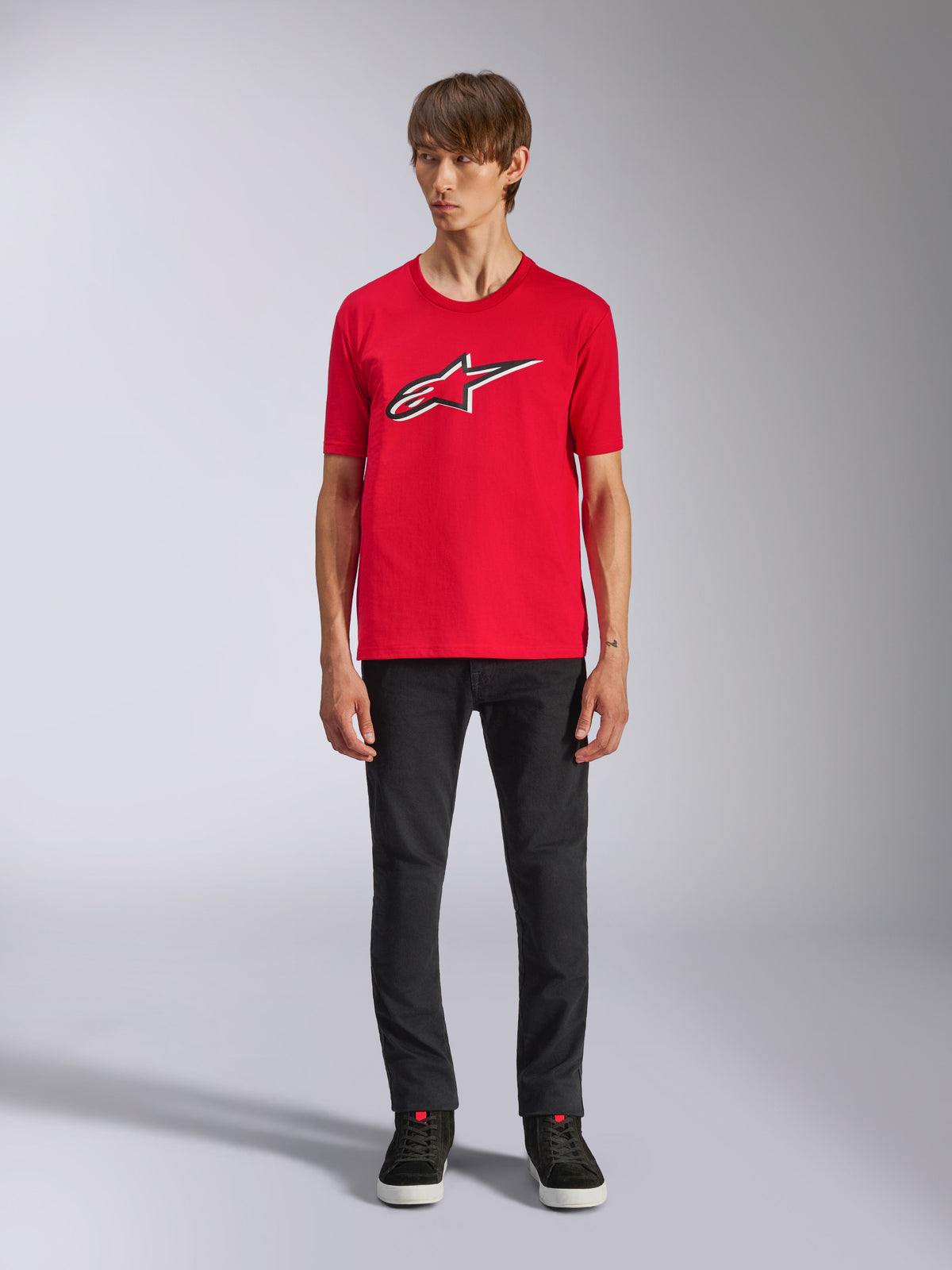 Alpinestars Ageless Shadow CSF Tee, kortærmet t-shirt, rød, Ageless-logo foran med hvide og sorte konturer, bæres af en model med sorte bukser og sneakers, casual motorsport-streetwear