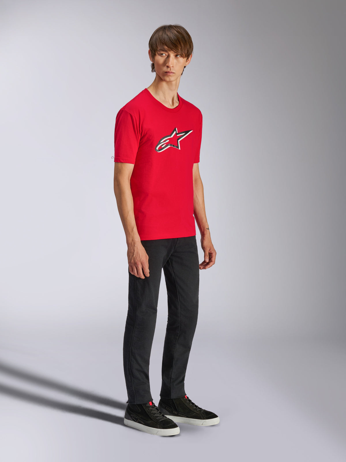 Alpinestars Ageless Shadow CSF Tee, rød kortærmet t-shirt, med et stort Ageless-logo på brystet, båret af en model med sorte bukser og sneakers, afslappet motorsport streetwear