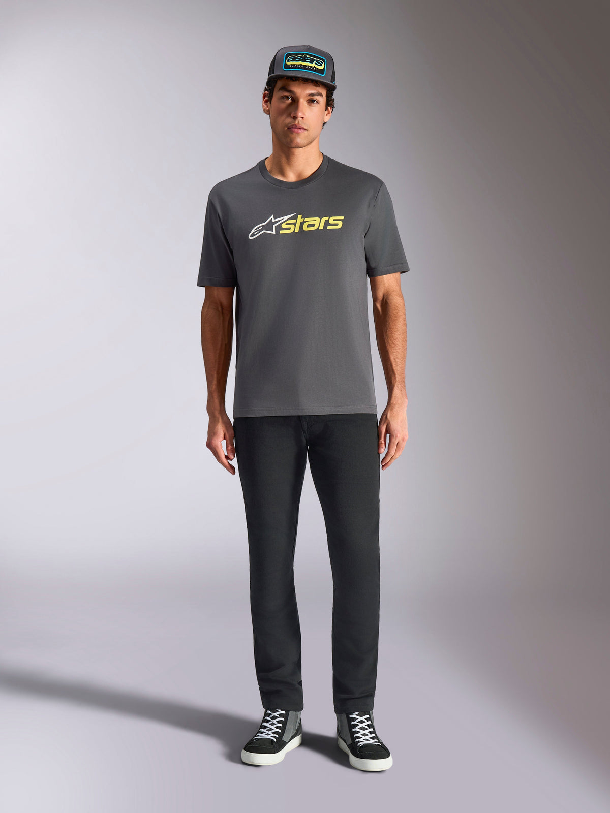 Alpinestars Blaze 2.0 CSF Tee, kortærmet T-shirt, koksgrå med hvidt og hi-vis gult logo, båret med sorte bukser og en matchende trucker-kasket, afslappet motorsport-livsstil