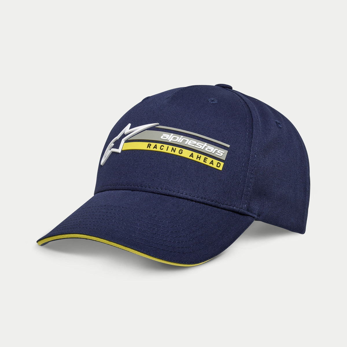 Alpinestars Par Hat, navyblå snapback-kasket, kurvet skygge med gul sandwich-kant, 3D-broderet logo med 'Racing Ahead'-grafik, afslappet motorsportsinspireret hovedbeklædning