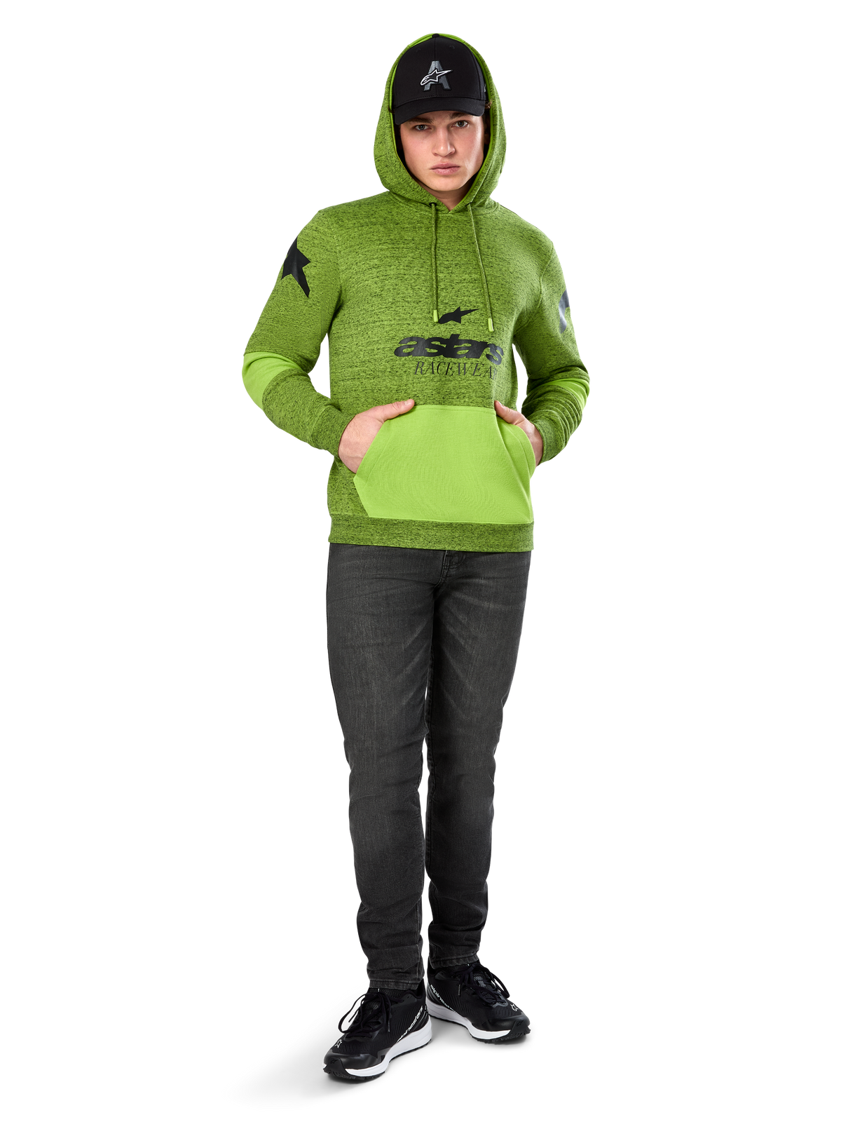 Alpinestars Perpetuate Hoodie, limegrøn meleret pullover-fleece med kontrasterende lysegrøn kængurulomme og ærmepaneler, sort 'astars' grafik på fronten, stylet med en sort kasket og mørke jeans, afslappet motorsport-inspireret streetwear