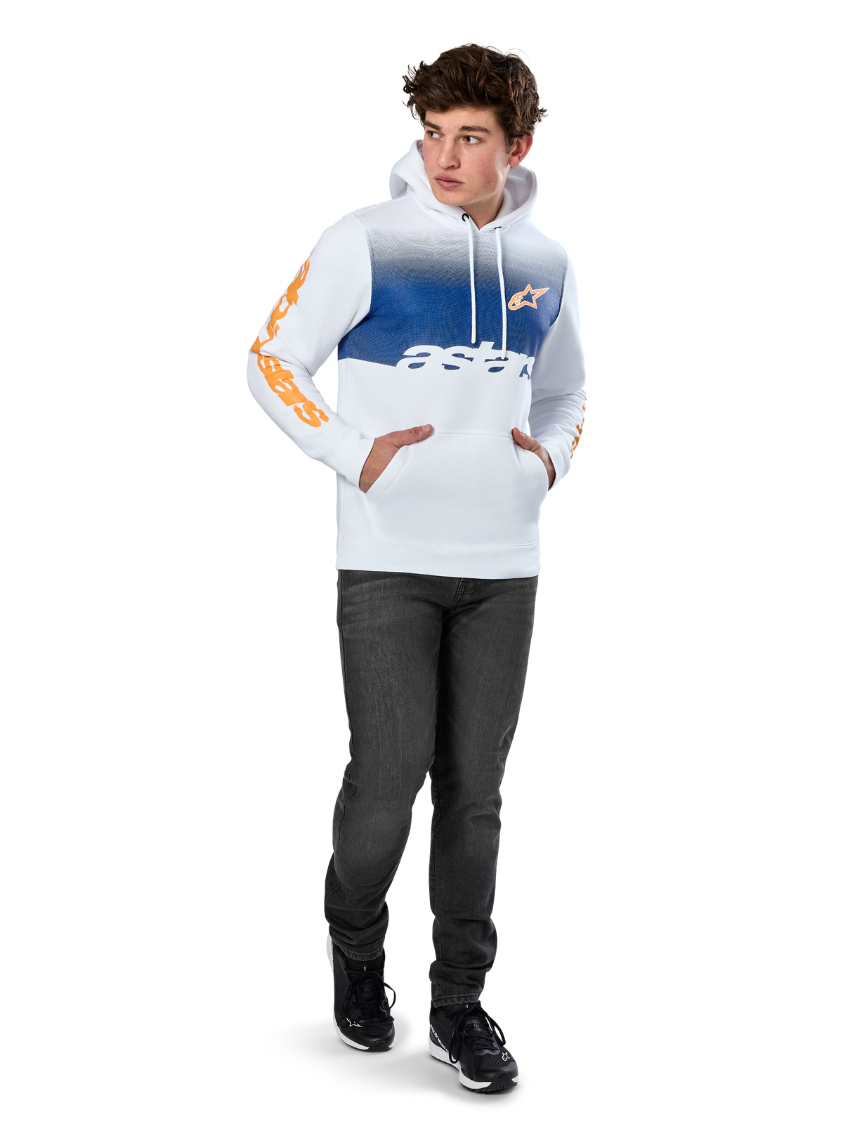 Alpinestars Specter hættetrøje, hvid pullover-fleece med blåt graduerings-fade-print, orange HD-logo foran og ordmærker på ærmerne, med kængurulomme og hætte med snøre, båret med mørke jeans for et afslappet motorsportsinspireret look