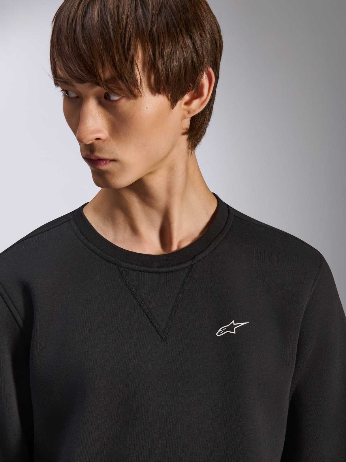 Alpinestars Positive Crew sweatshirt, sort crewneck med V-syning ved halsen, lille hvidt Alpinestars-logo på venstre bryst, afslappet motorsport-inspireret streetwear