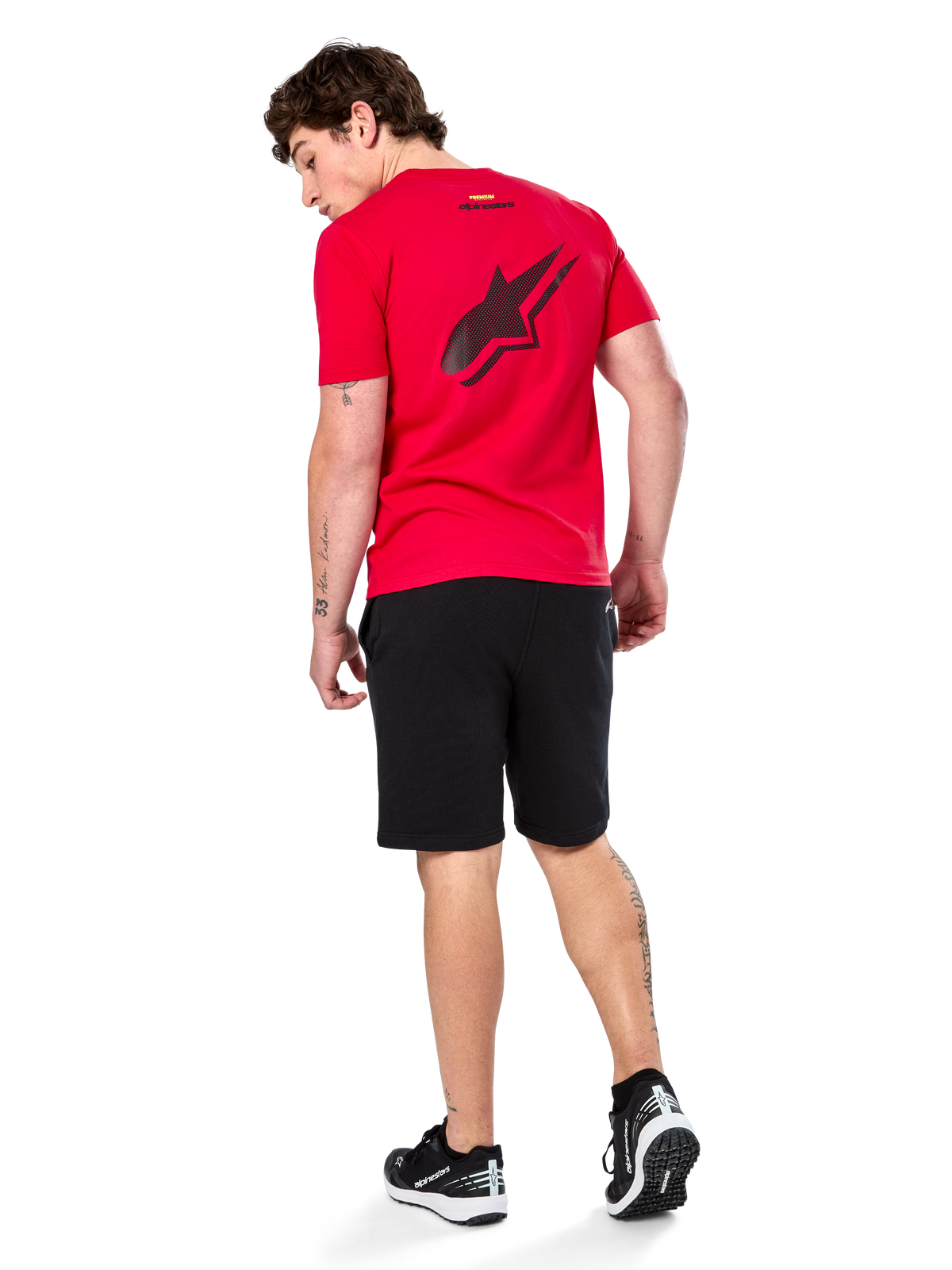 Alpinestars Formulate Csf Tee, kortærmet t-shirt, rød, stort sort perforeret Astars-logo på ryggen, bæres med sorte shorts og sneakers, afslappet motorsport-inspireret streetwear