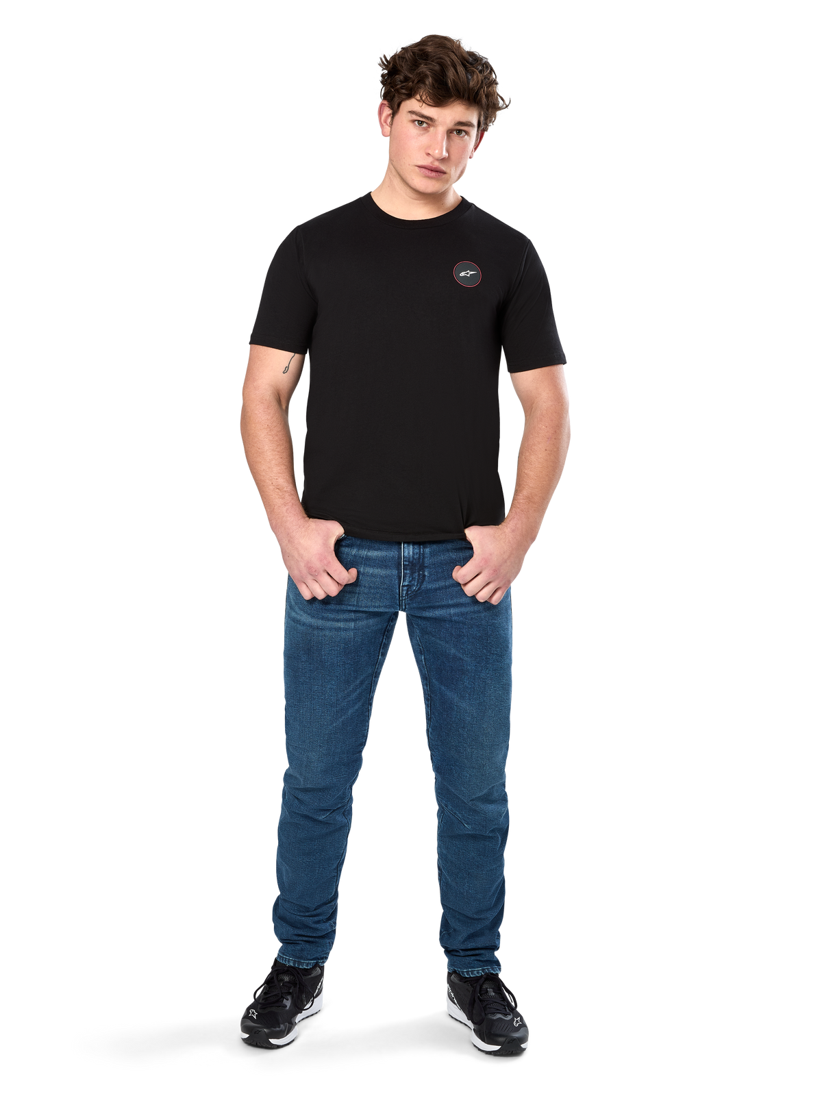 Alpinestars Dot Carbon CSF Tee, kortærmet t-shirt, sort, lille cirkulært Astars Dot-logo på brystet, båret med blå jeans og sorte sneakers, afslappet motorsport streetwear
