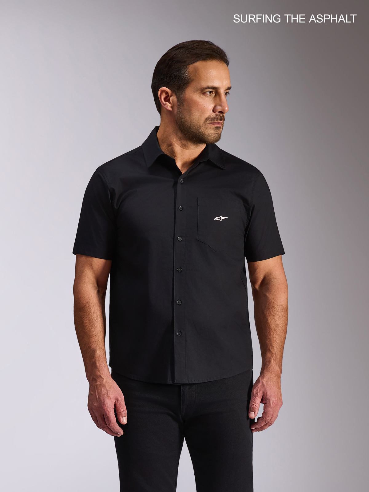 Alpinestars Strive Woven Skjorte, sort kortærmet casual skjorte båret af mandlig model med brystlomme og hvidt Alpinestars-logo