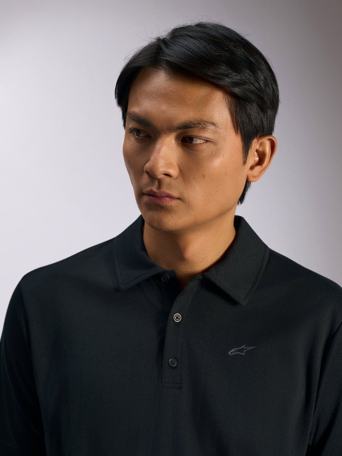Alpinestars Impetus Sport Polo, sort sportspolo, mock mesh-stof med tre knapper og selvkrave, diskret Astars-logo på brystet, afslappet motorsport lifestyle-beklædning