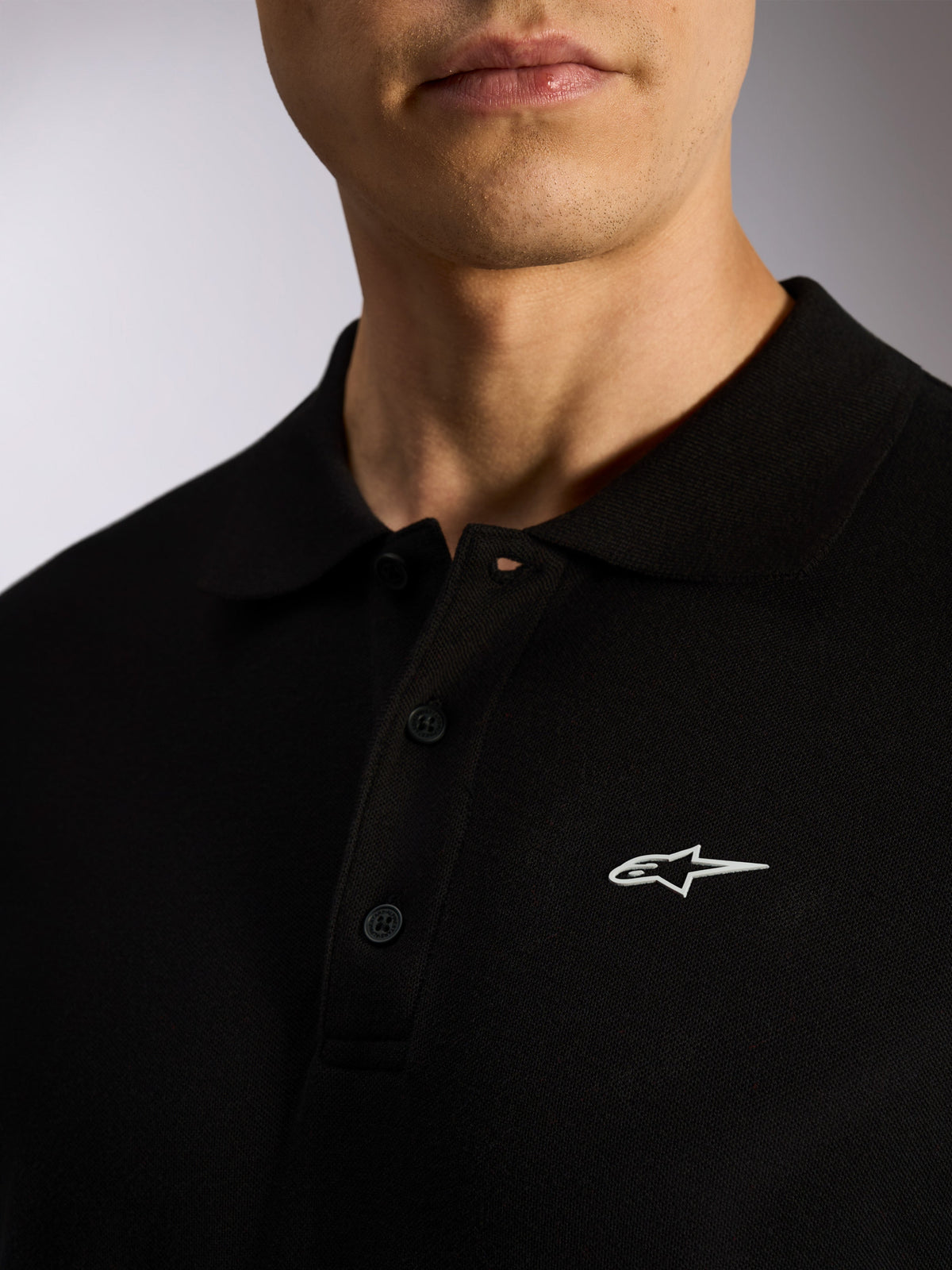 Alpinestars Endeavor Classic Polo, sort piqué kortærmet polo, stolpelukning med tre knapper, ribkrave, hvidt Astars-logo HD-print, afslappet motorsport-inspireret streetwear