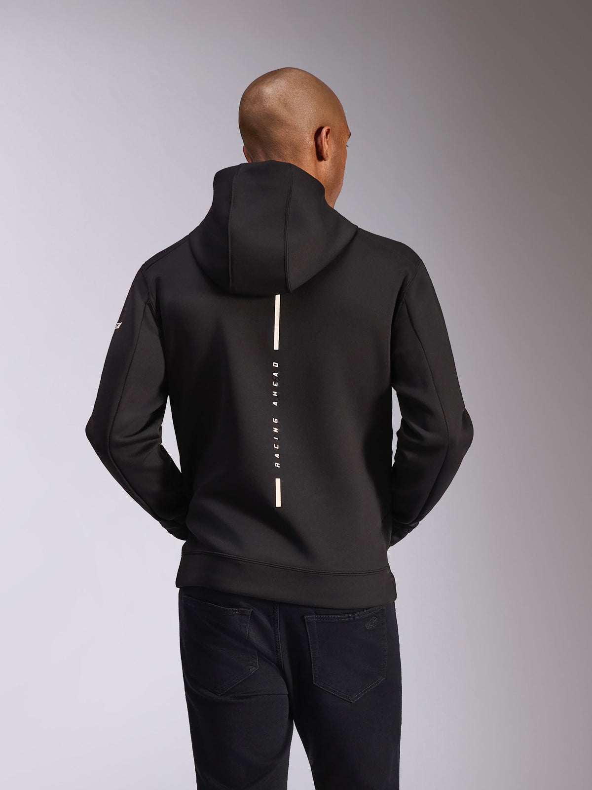 Alpinestars Insight hættetrøje, set bagfra, sort, lodret hvid stribe med 'RACING AHEAD'-tekst, wordmark-branding på ærmet, afslappet motorsport-inspireret streetwear