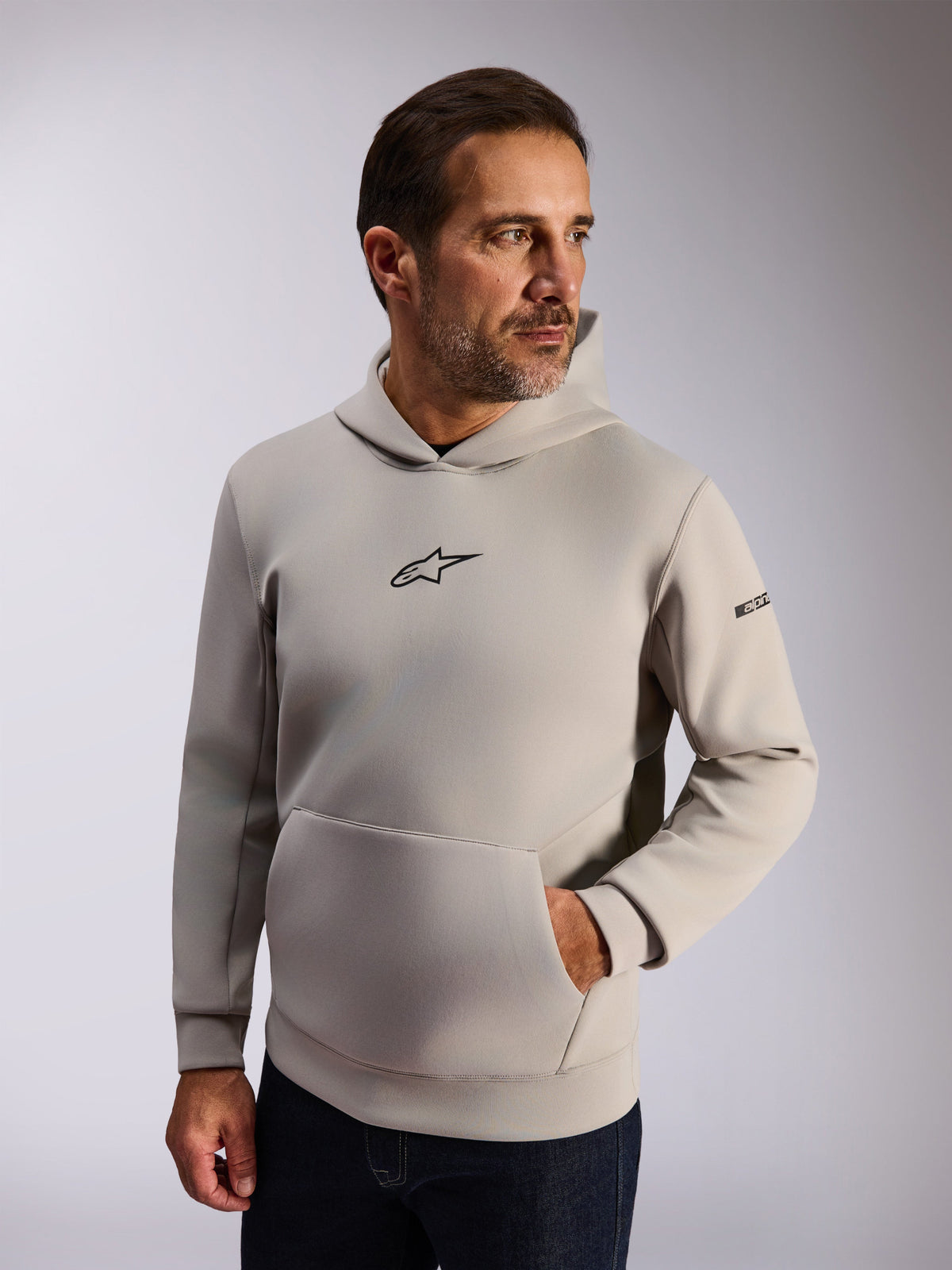 Alpinestars Insight Hoodie, casual lifestyle streetwear, cementgrå fleece, sort Astars-logo på fronten, kængurulomme, wordmark på ærmet, mesh-foret hætte, moderne motorsport-inspireret beklædning