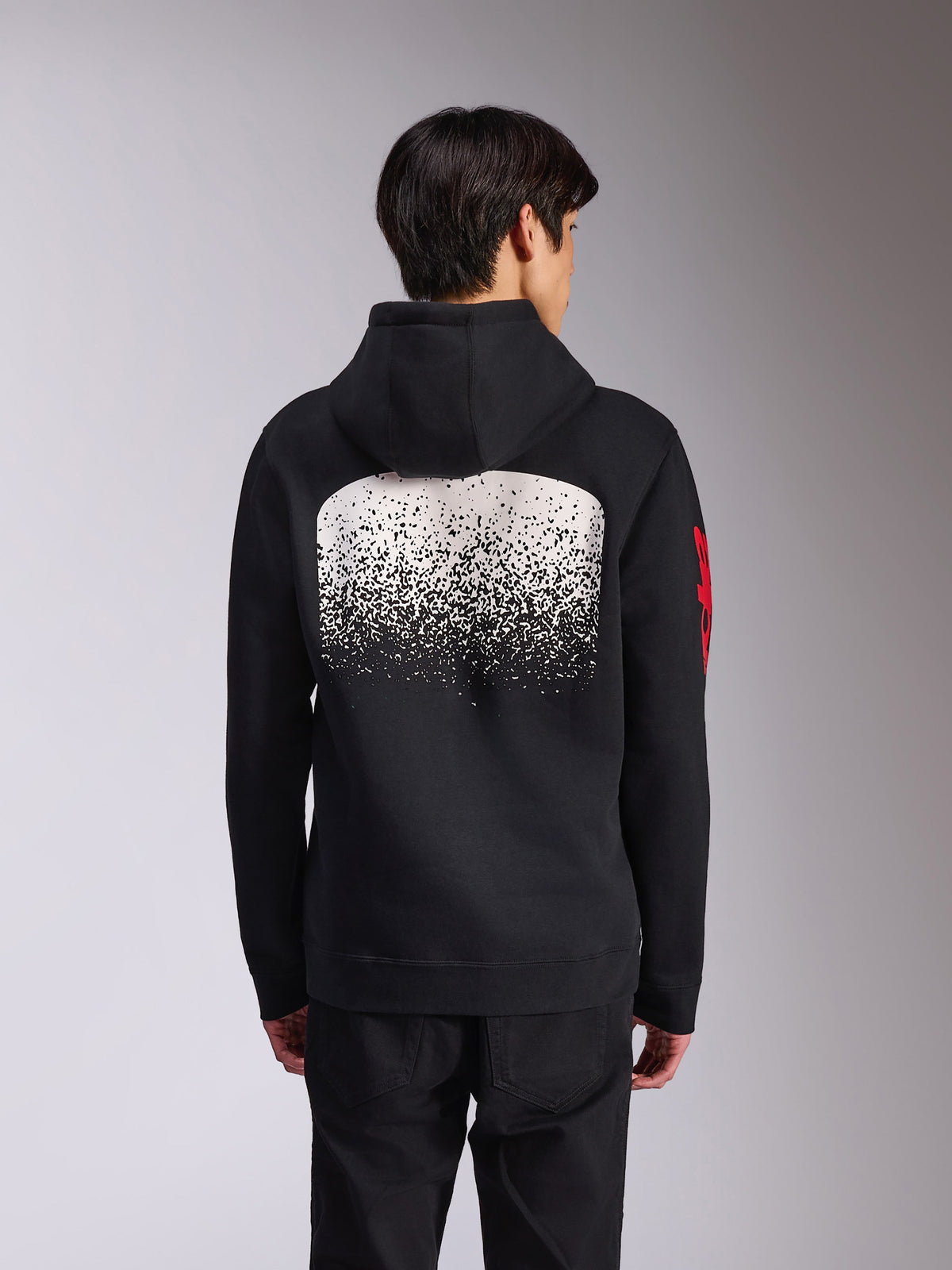 Alpinestars Obsessed hættetrøje, sort pullover-fleece set bagfra, med en stor hvid spættet MX-gradueringsgrafik på ryggen og røde Alpinestars ord-logoer på ærmerne, afslappet motorsport-inspireret streetwear