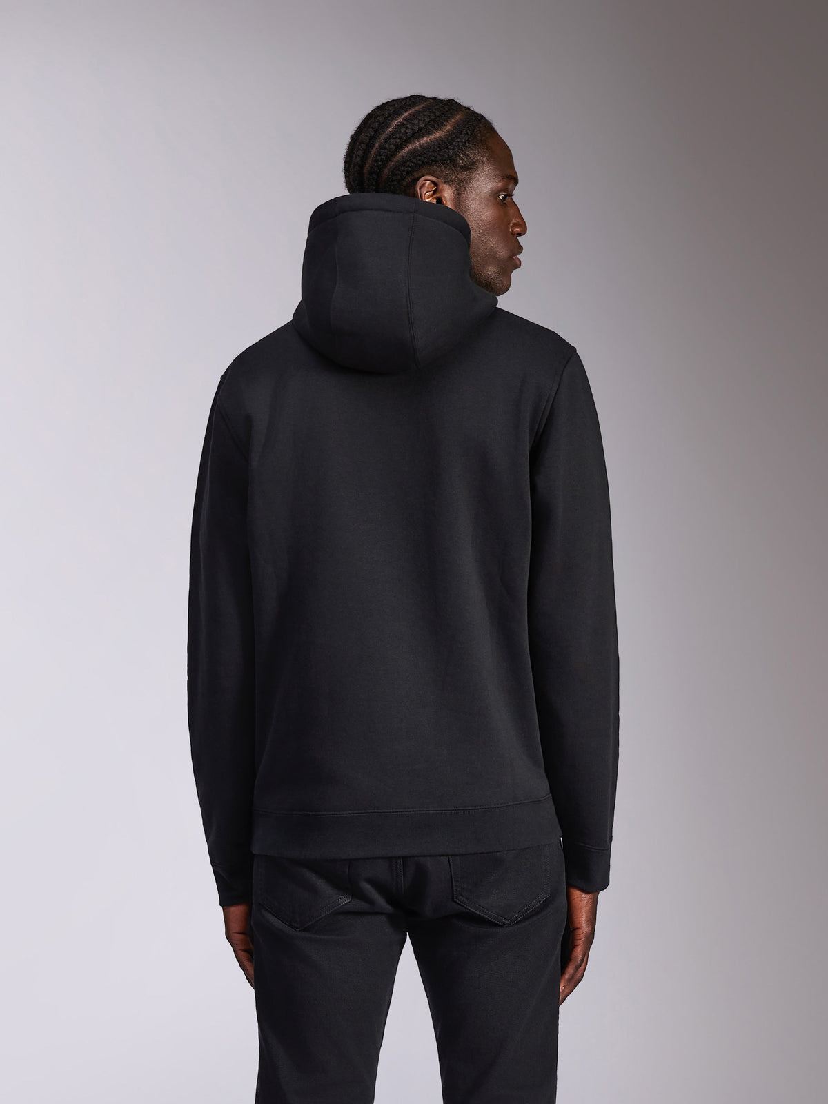 Alpinestars Pulse hættetrøje, sort, set bagfra på model, afslappet streetwear, pullover-fleece med hætte i ensfarvet sort design, ribstrikkede manchetter og kant, kombineret med sorte bukser