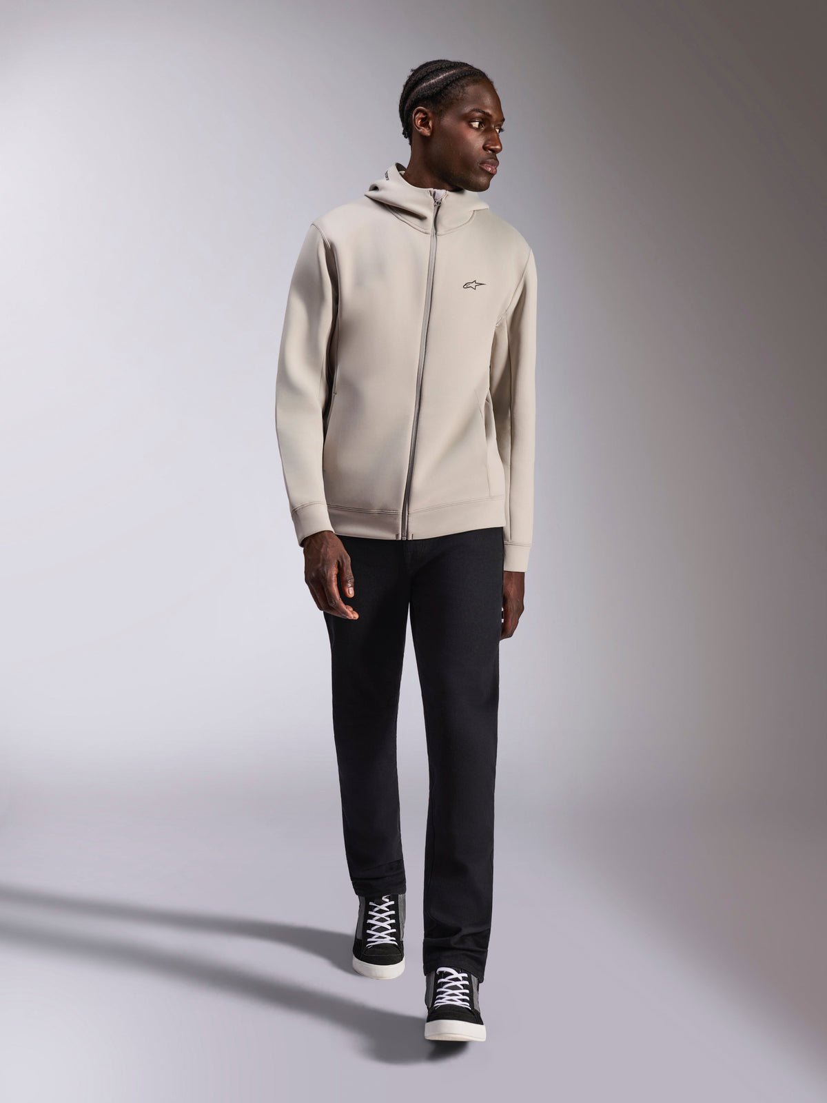 Alpinestars Cypher Hoodie, hættetrøje med gennemgående lynlås i dobbeltsidet fleece, Cement-grå, bæres af model med sorte bukser og sort-hvide sneakers, med høj mesh-foret hætte og lille Astars-logo på brystet, moderne casual streetwear