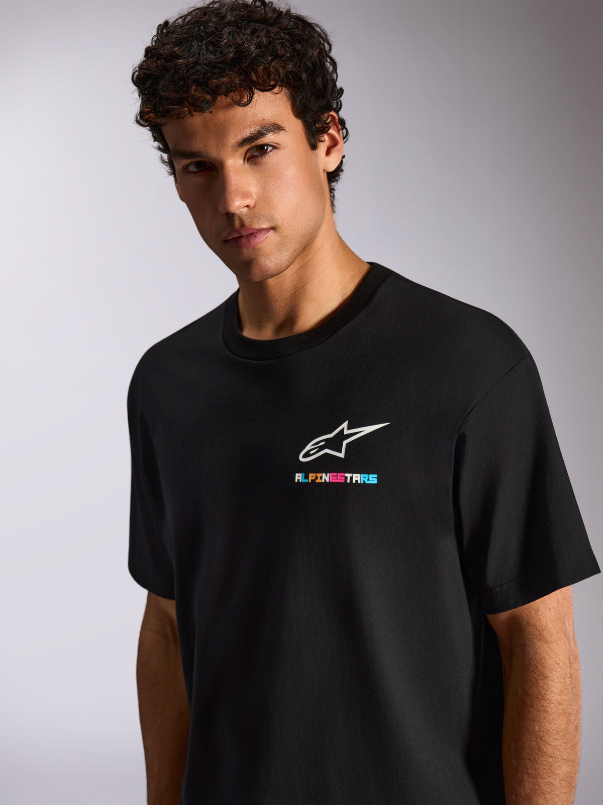 Alpinestars Wild Oversized CSF Tee, sort kortærmet t-shirt, med hvidt Astars-logo og livlig flerfarvet branding på brystet, afslappet motorsport streetwear