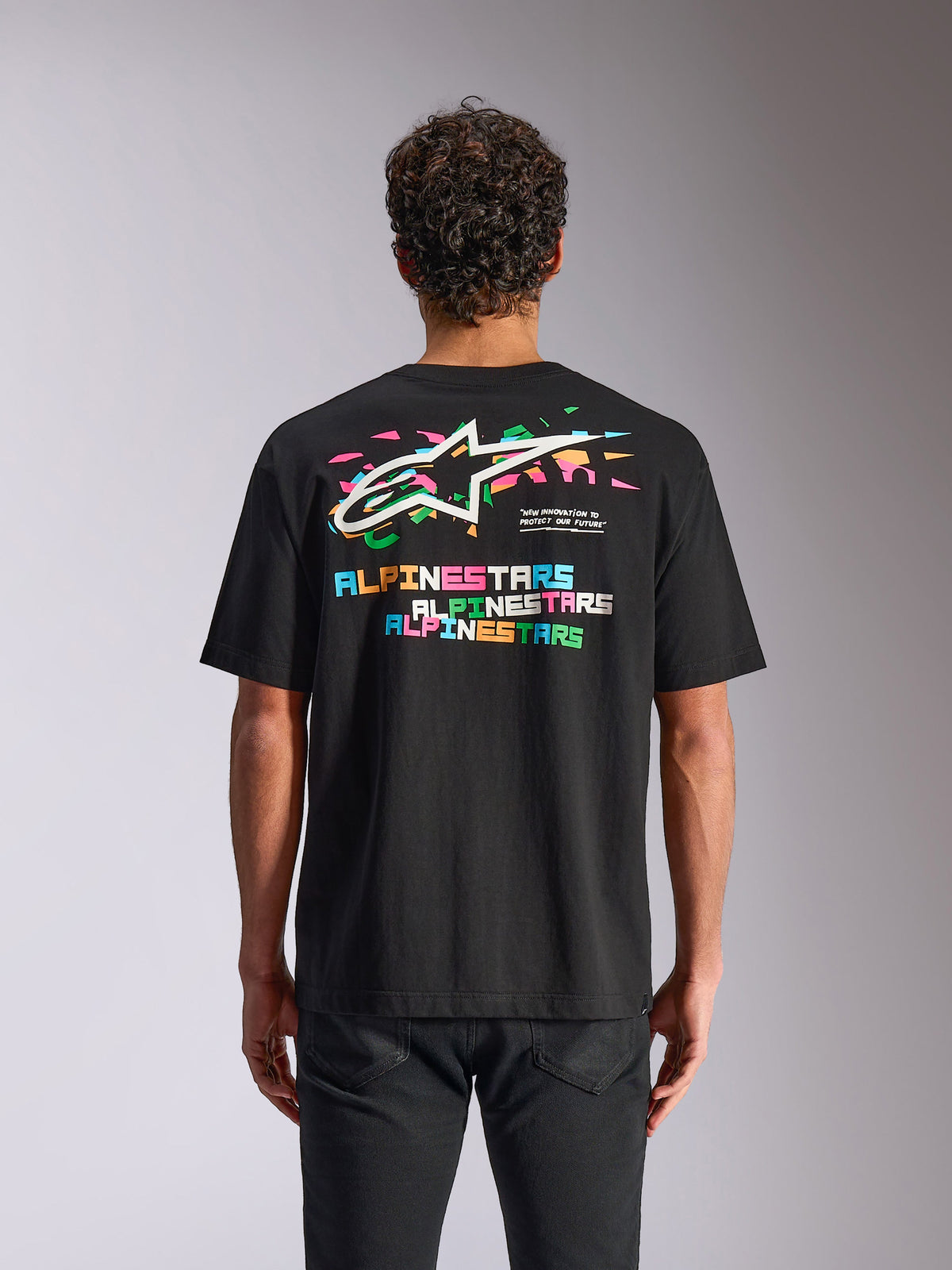 Alpinestars Wild Oversized CSF Tee, kortærmet T-shirt, sort, set bagfra viser livligt flerfarvet Astars-logo og grafiske elementer, afslappet motorsport-streetwear