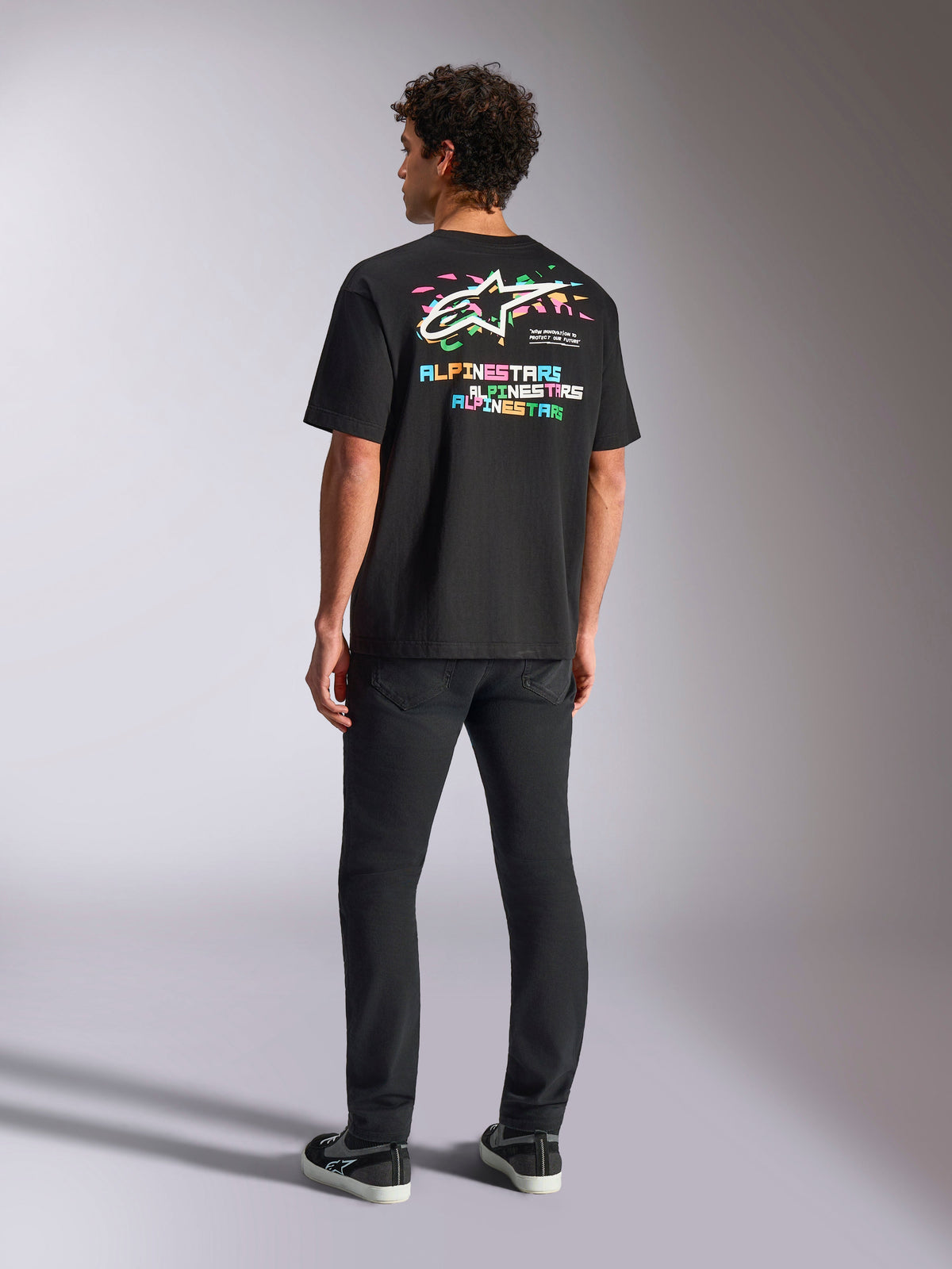 Alpinestars Wild Oversized CSF Tee, kortærmet T-shirt, sort, med en stor flerfarvet grafik på ryggen med Astars-logo og farverige bogstaver, oversized pasform, båret med sorte slim-fit bukser for et afslappet streetwear-look