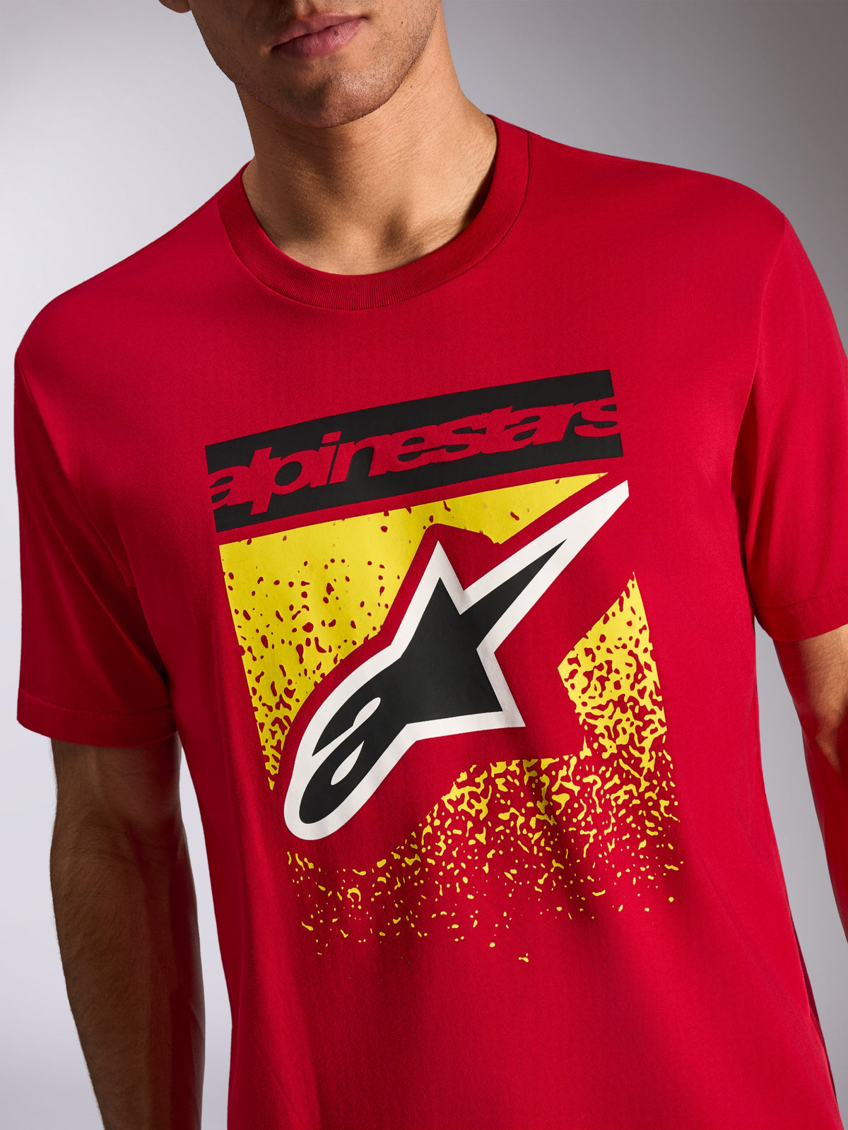 Alpinestars Noka CSF Tee, kortærmet t-shirt, rød, frontgrafik med sort Alpinestars-tekst og Astars-logo over gult spættet design, casual motorsport-streetwear