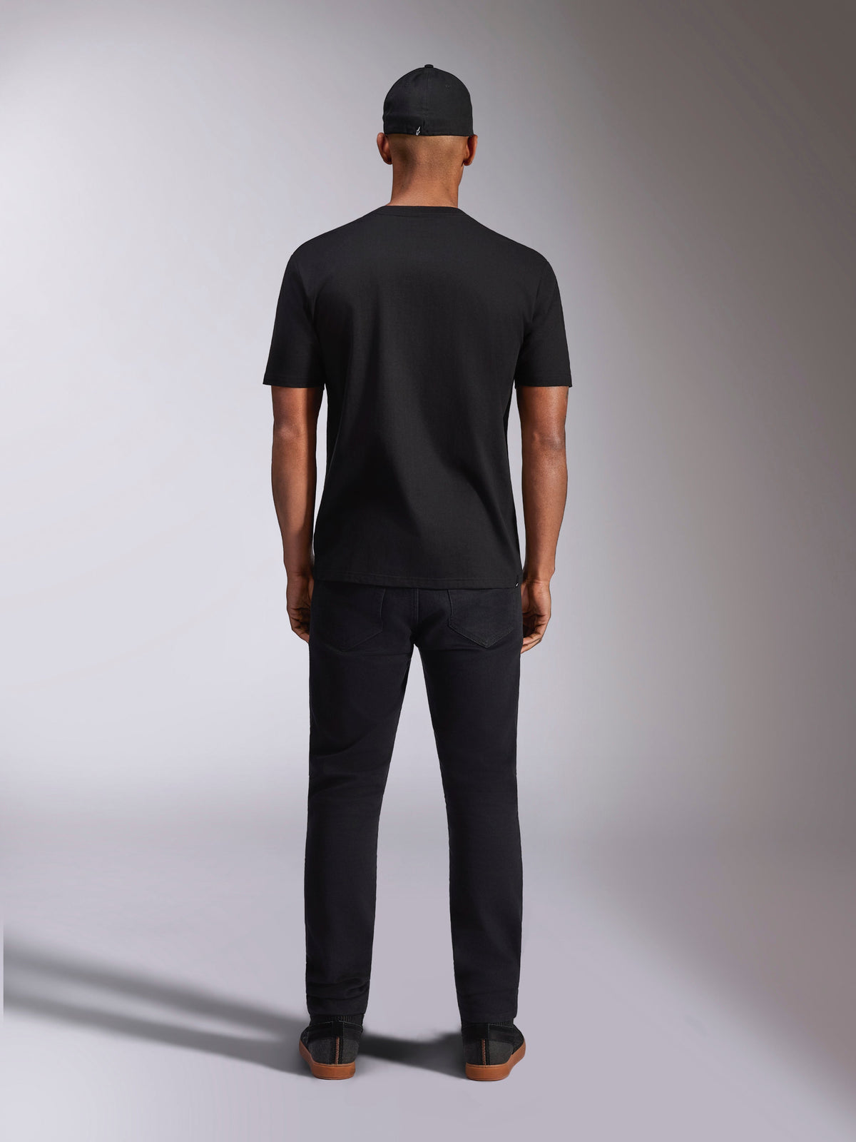 Alpinestars Plate CSF Tee, kortærmet t-shirt, sort, set bagfra på model, bæres med sort kasket og bukser, afslappet motorsport streetwear