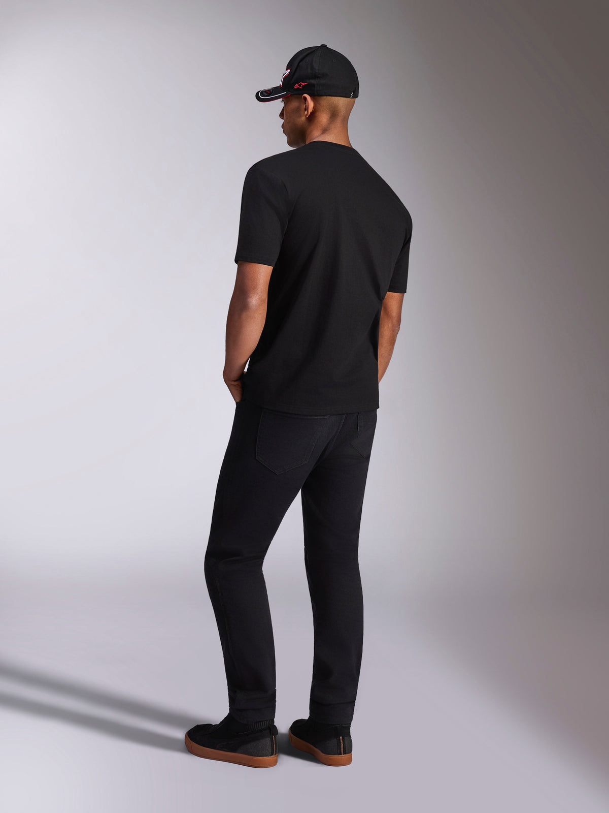 Alpinestars Plate CSF Tee, kortærmet T-shirt, sort, set bagfra på model iført sorte bukser og kasket, casual motorsport streetwear