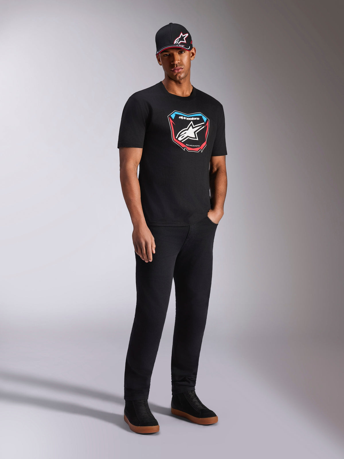 Alpinestars Plate CSF Tee, kortærmet T-shirt, sort, farverig MX-plade grafik på fronten med stjernelogo, båret af model med sort logo-kasket og bukser, afslappet motorsport-inspireret streetwear
