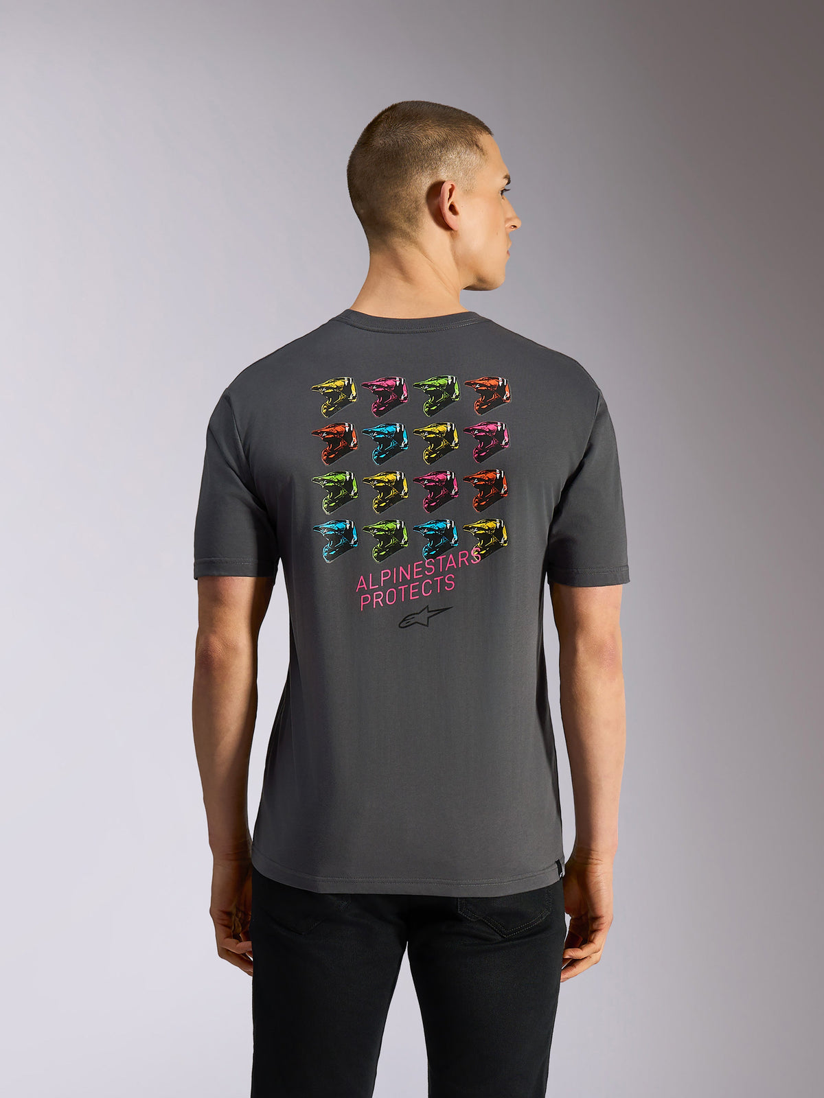 Alpinestars Pop Helmet CSF Tee, kortærmet t-shirt, grå, set bagfra med et farverigt gitter af 16 M10-hjelme og lyserød "ALPINESTARS PROTECTS"-tekst på ryggen, afslappet motorsport-inspireret streetwear