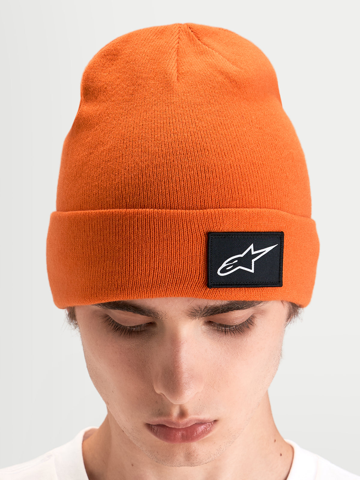 Alpinestars Augment Cuff Beanie, orange sportswear-beanie med dyb pasform og sort vævet Astars-logo på opslaget, båret af model