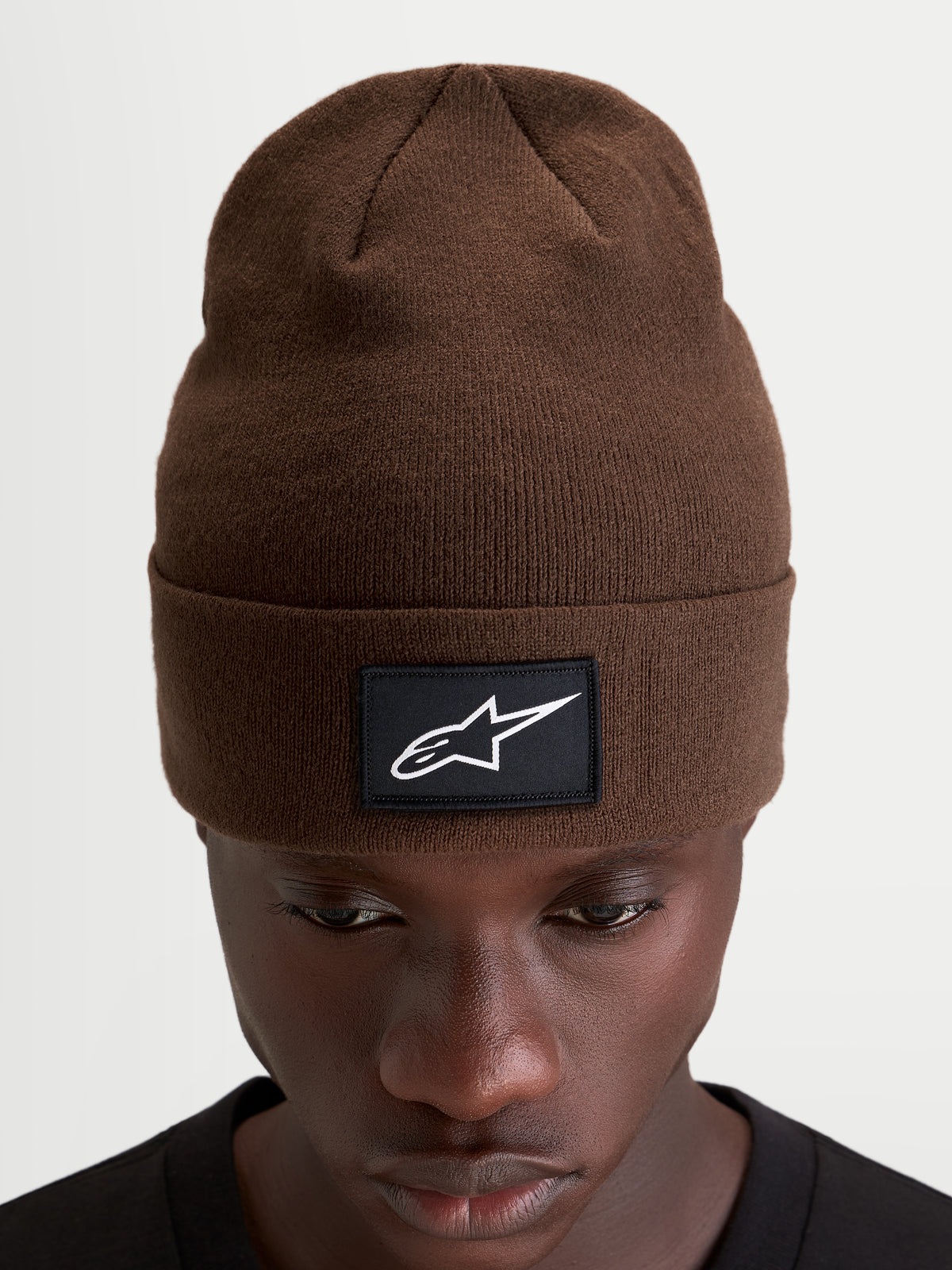 Alpinestars Augment Cuff Beanie, brun beanie med strikket jersey-søm og vævet sort-hvidt Astars-logopatch, båret af model