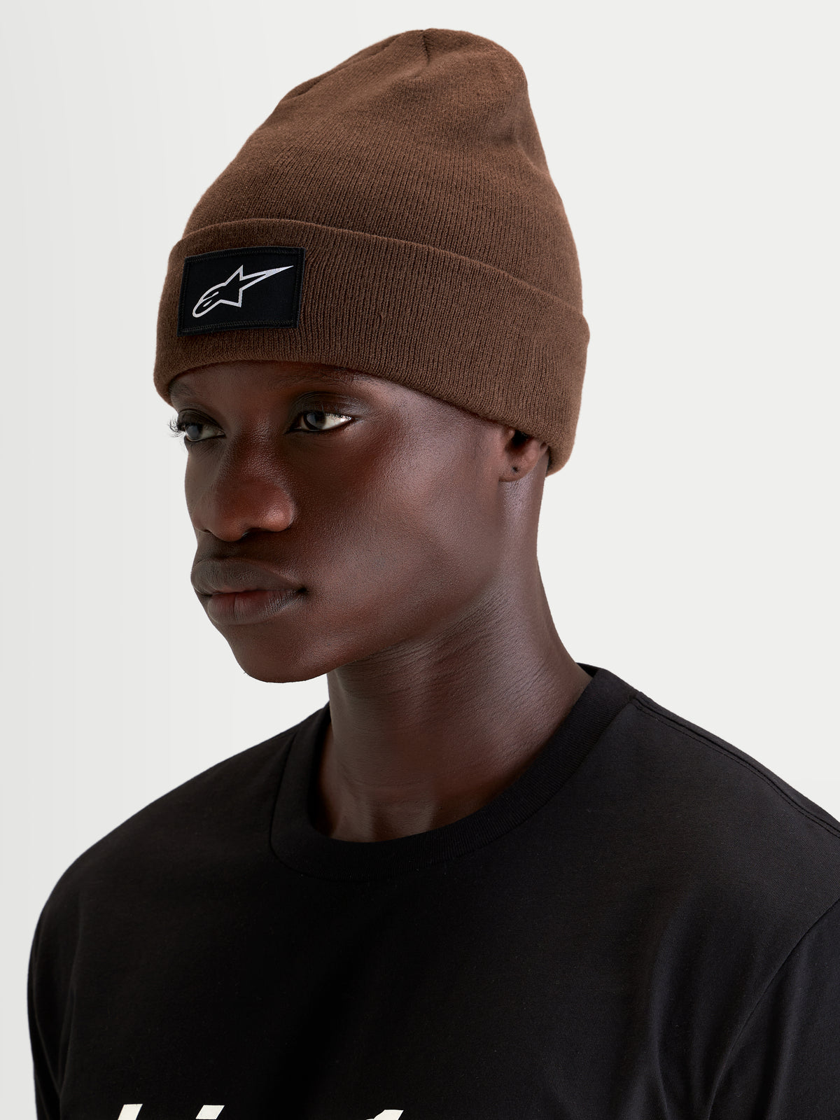 Alpinestars Augment Cuff Beanie, brun strikket hue med sort og hvidt vævet Alpinestars-logopatch på kanten, båret af model