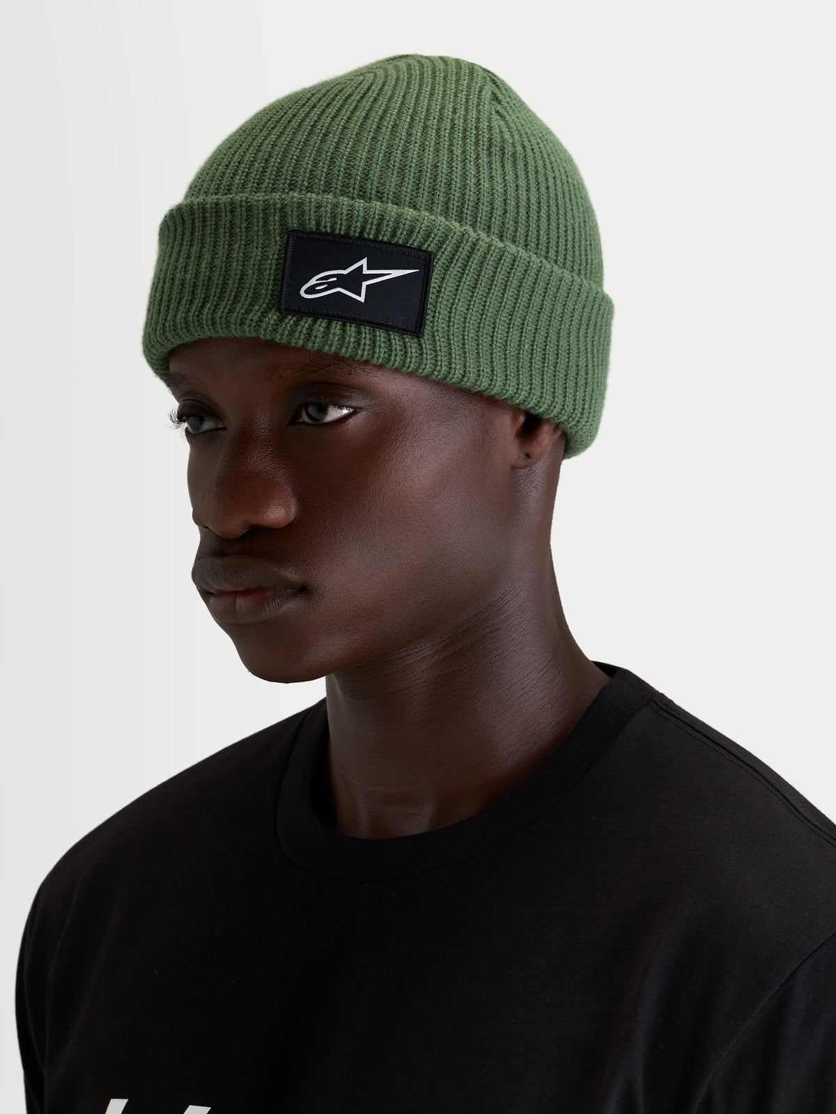 Alpinestars Unload Rib Cuff Beanie, ærtegrøn hue, strikket jerseystruktur, sort og hvidt SAstars-logo på fronten, båret af model