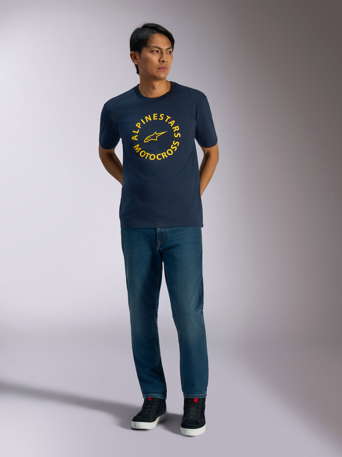 Alpinestars MX CSF Tee, kortærmet t-shirt, mørkeblå med gul cirkulær Alpinestars Motocross-grafik, båret af en model med blå jeans og sorte sneakers, afslappet motorsport streetwear