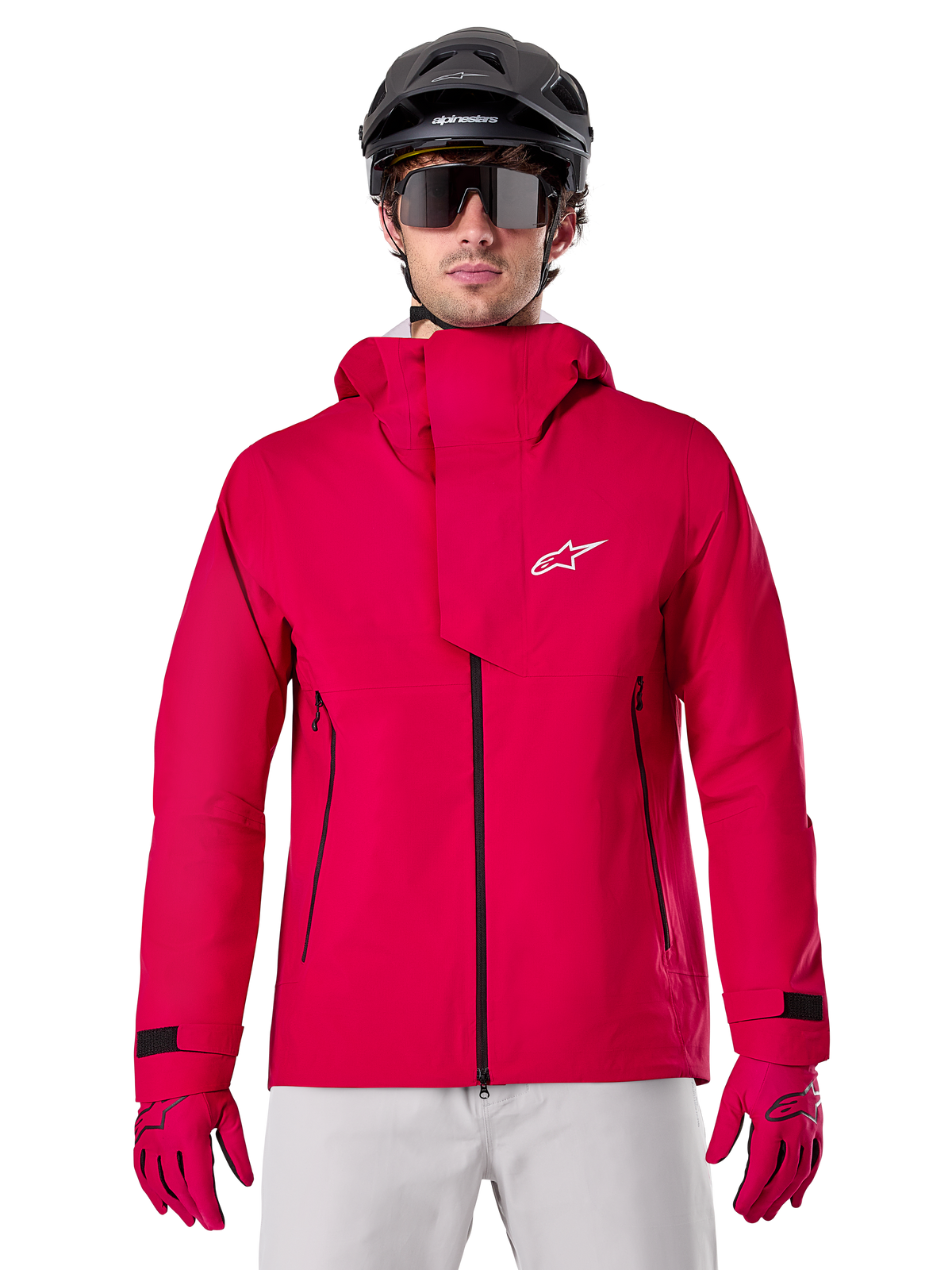 Alpinestars A-Dura Elite vandtæt jakke, MTB-regnjakke, Red Fluo, høj krave med hvidt Alpinestars logo, sorte lynlåsdetaljer, bæres med matchende handsker og sort cykelhjelm, teknisk vandtæt cykeludstyr