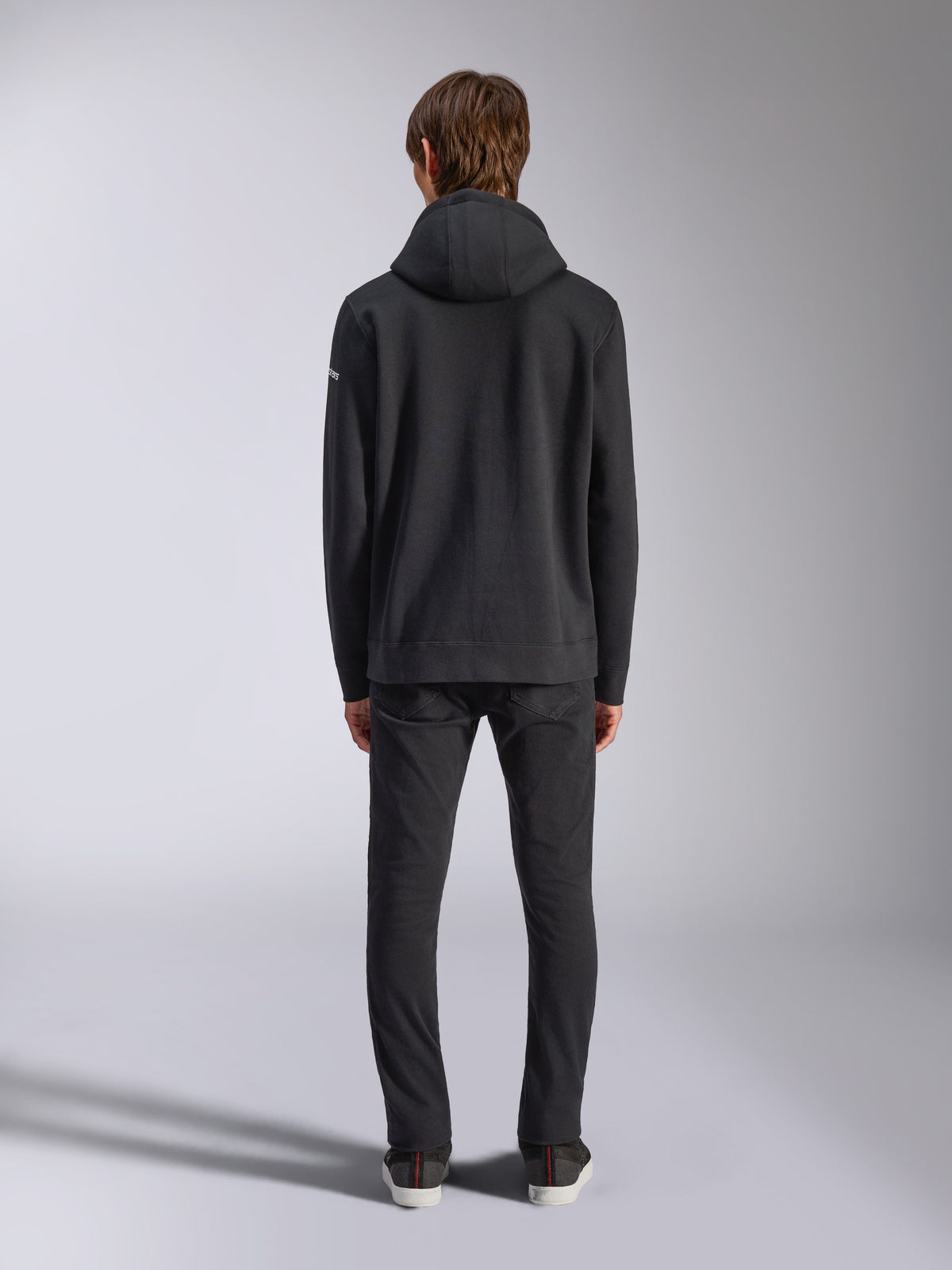 Alpinestars Frontal Hoodie, casual streetwear, sort, set bagfra af model iført pullover fleece-hættetrøje, med ribkant og manchetter, lille hvidt tekstlogo på ærmet, kombineret med sorte bukser