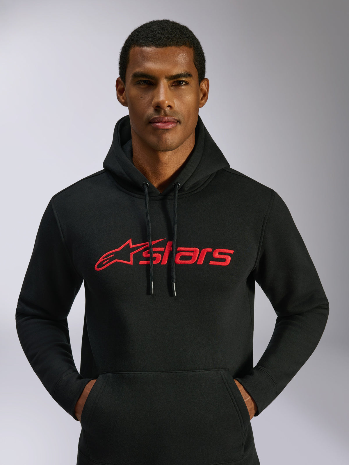 Alpinestars Blaze V3 hættetrøje, casual streetwear, sort med rødt Alpinestars-logo på brystet, båret af en mand, hætte med snoretræk, lange ærmer, moderne motorsport-inspireret design