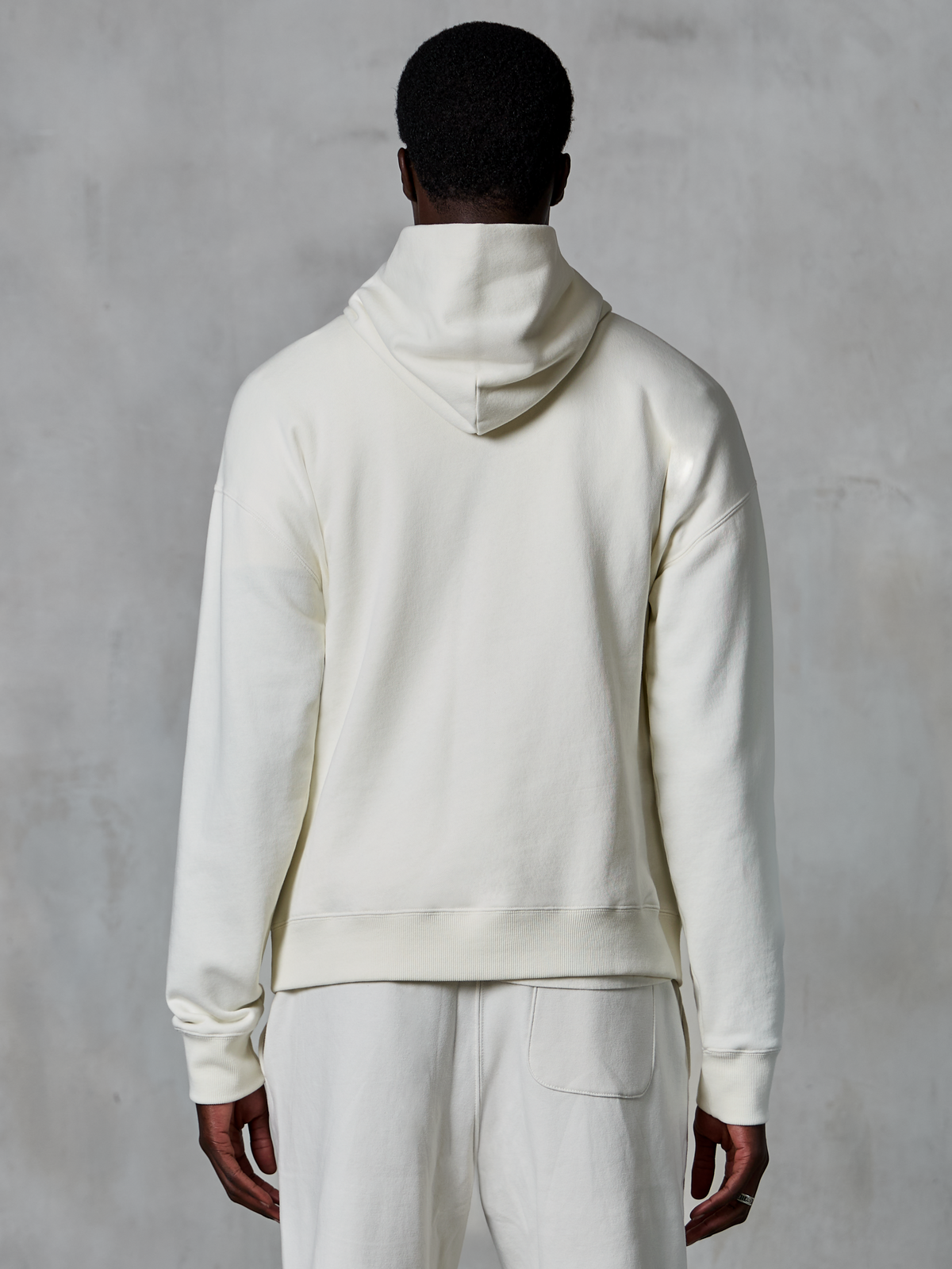 Alpinestars Essentials Ageless Hoodie, off-white pullover hoodie, back view on model, clean minimalist design, matching casual pants, relaxed fit for everyday comfort