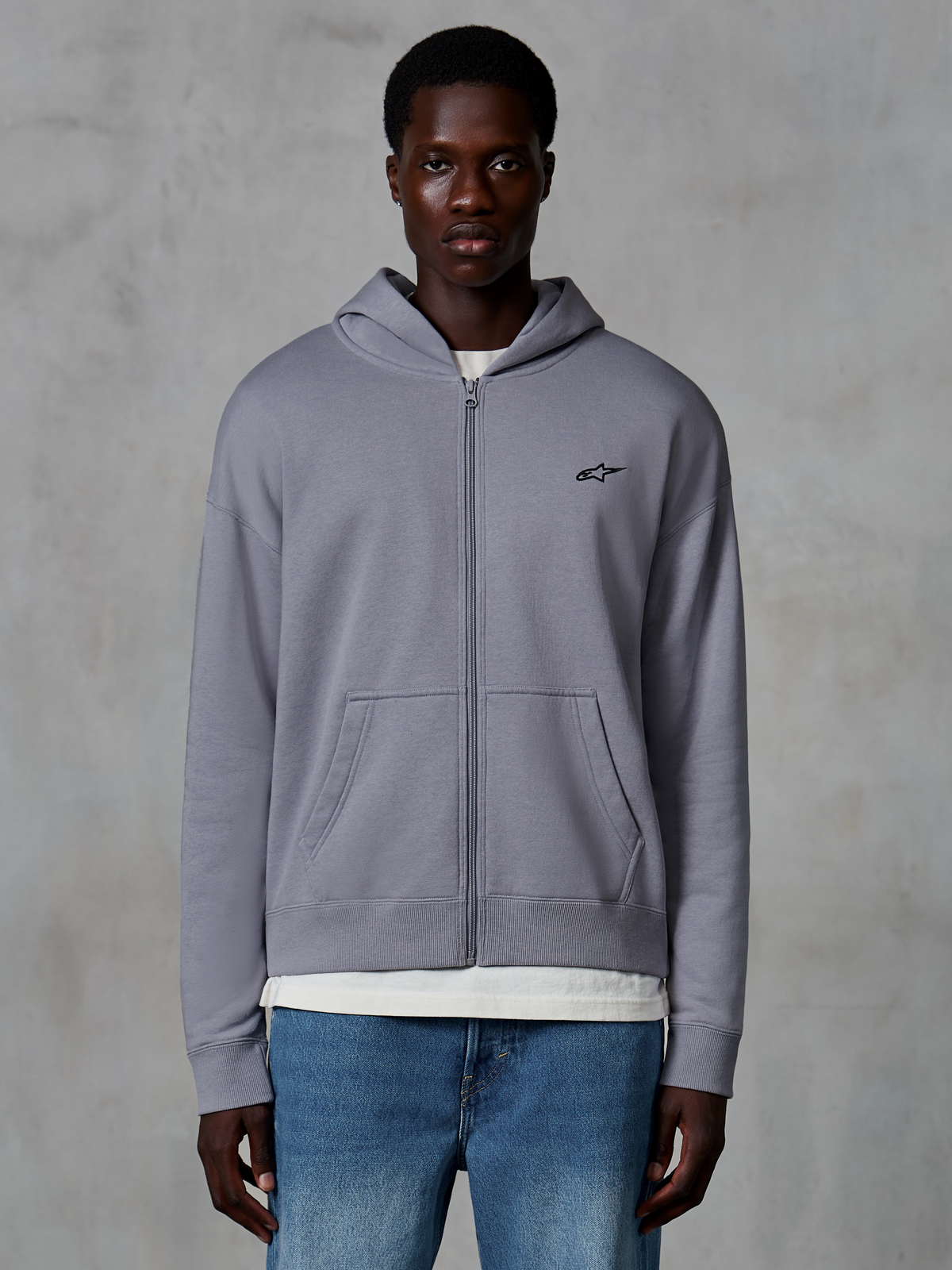 Alpinestars Essentials Ageless Zip hættetrøje, sølv, afslappet streetwear båret af model, fleece med fuld lynlås og lille sort Astars-logo på brystet, kængurulommer, design med afslappet pasform