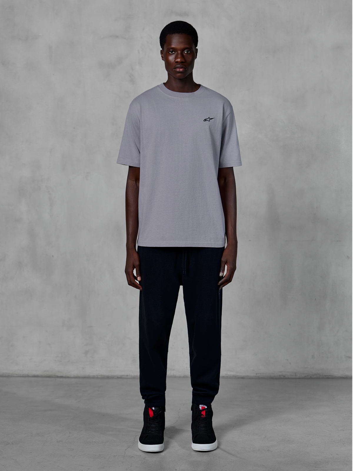Alpinestars Essentials Ageless SS Tee, kortærmet t-shirt, Silver, med et lille sort logo på brystet, stylet med sorte joggingbukser og sneakers, afslappet motorsport streetwear