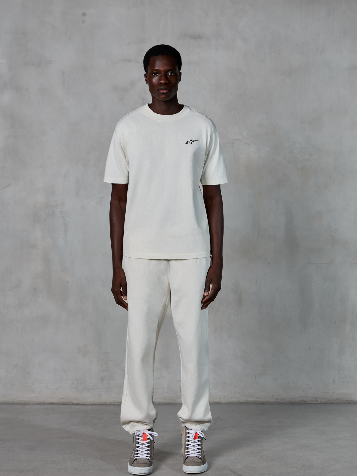 Alpinestars Essentials Ageless SS Tee, kortærmet T-shirt, råhvid, med et lille sort Alpinestars-logo på brystet, stylet med matchende joggingbukser og sneakers for et afslappet livsstilslook