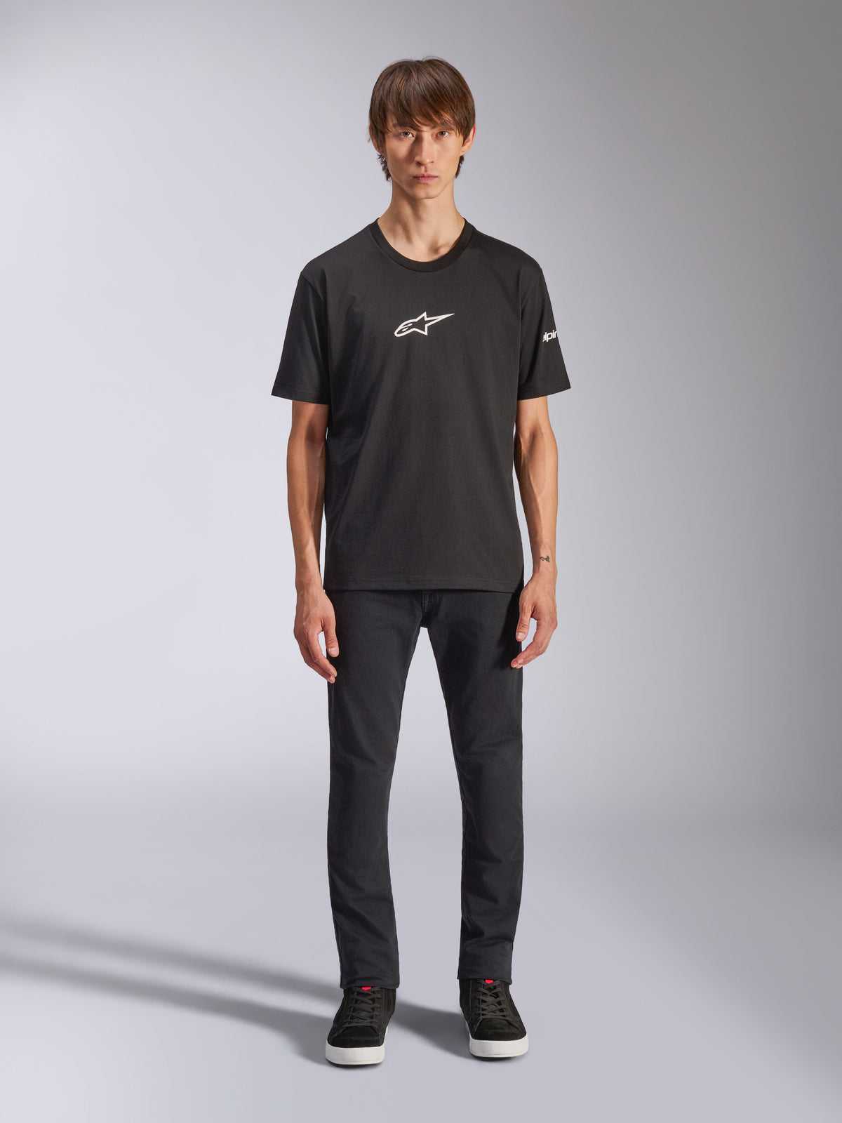 Alpinestars Frontal CSF Tee, kortærmet t-shirt, sort, hvidt Alpinestars-logo på brystet, båret af model med sorte bukser og sorte sko, afslappet performance-sportstøj