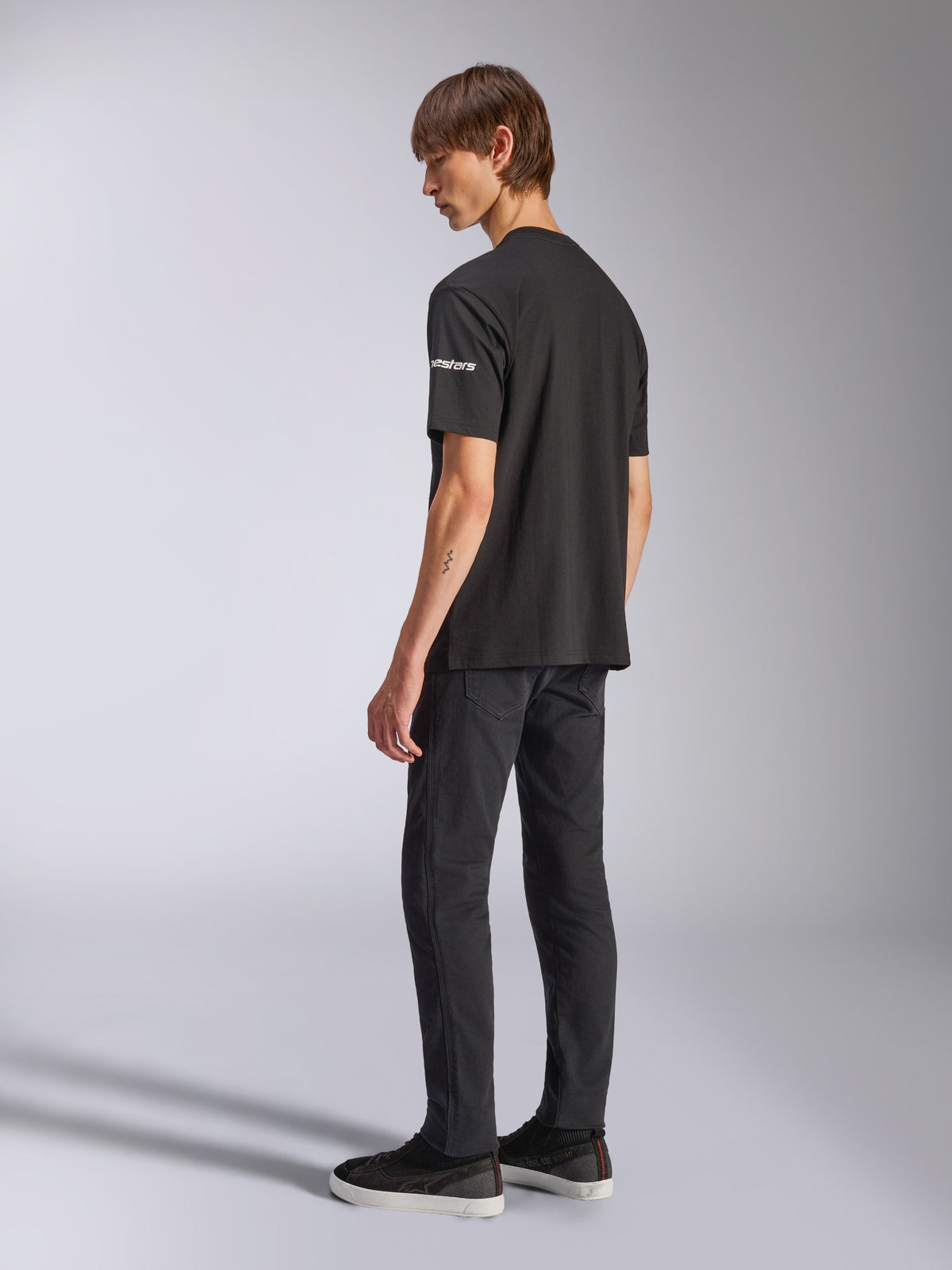 Alpinestars Frontal CSF Tee, kortærmet T-shirt, sort, hvidt Astars-logo på ærmet, båret af model med sorte bukser og sko, afslappet motorsport-inspireret design