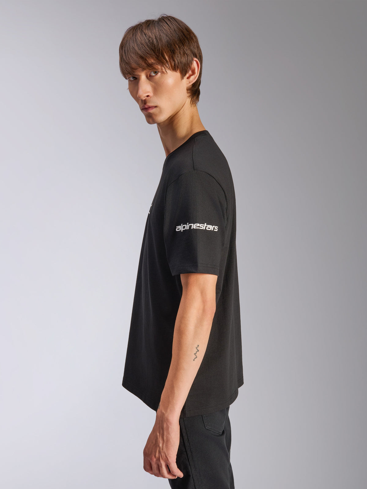 Alpinestars Frontal CSF Tee, kortærmet t-shirt, sort, hvidt Alpinestars-logo på ærmet, båret af model i profil, casual motorsport performance streetwear