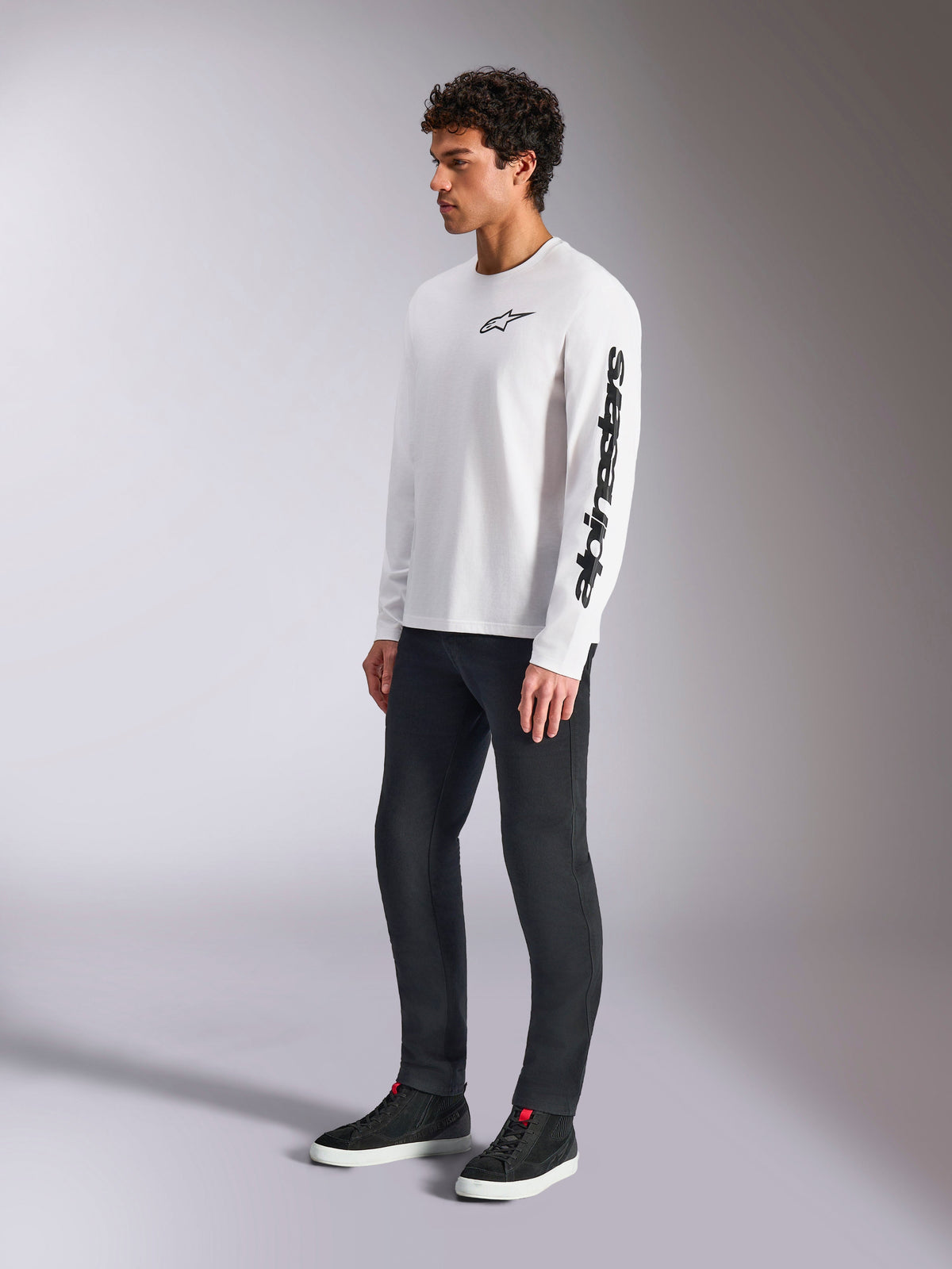 Alpinestars Trackside CSF Tee, Long Sleeve T-Shirt, White, Black star logo on chest and wordmark on left sleeve, worn by a male model with dark pants and sneakers, casual lifestyle sportswear