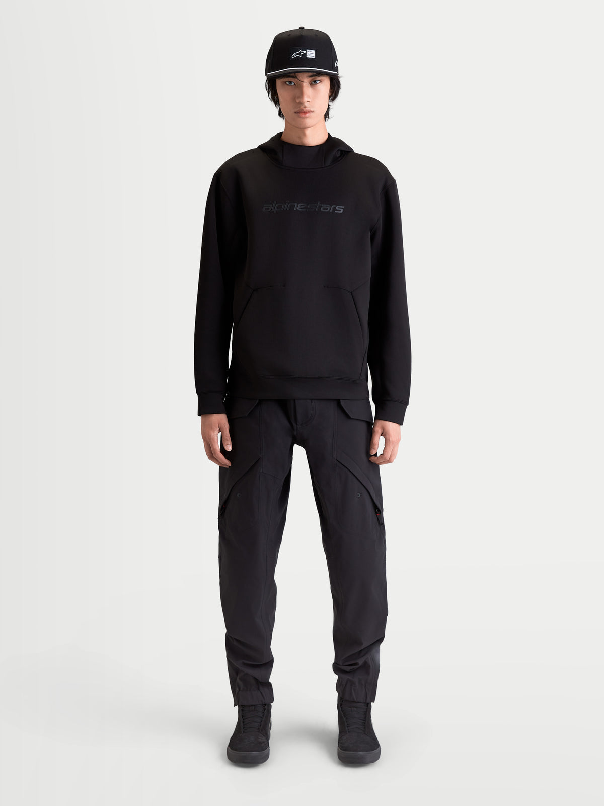 Alpinestars Datrix hættetrøje, premium sportstøj pullover til herre, sort, med tonal HD Alpinestars branding, tri-blend dobbeltsidet fleece og lomme med indsnitsdetalje, vist på model for en motorsport-inspireret hverdagsstil.