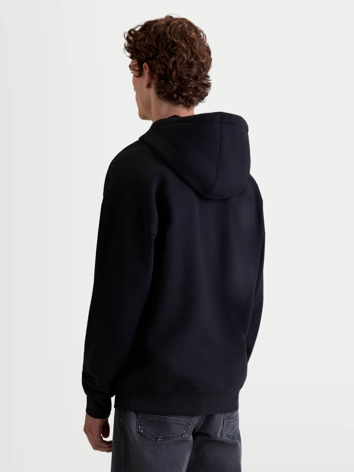 Alpinestars Prelude Oversized Hættetrøje, sort fleecepullover til sportswear, unisex, set bagfra med fokus på den afslappede silhuet, selvforet hætte samt ribmanchetter og ribkant for en ren finish.