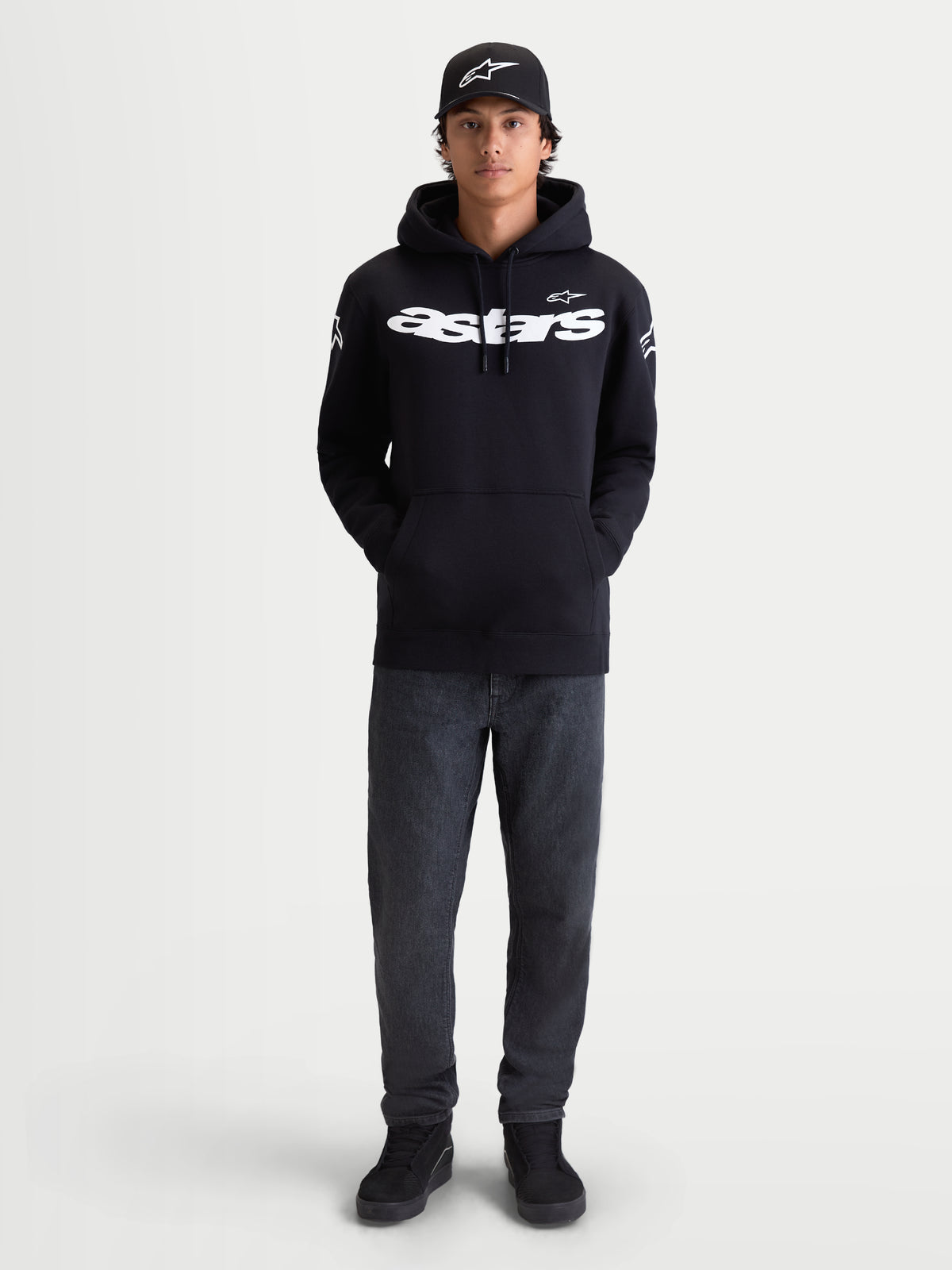 Alpinestars Velocifier hættetrøje, herrehættetrøje i sort fleece, afslappet sportstøj til hverdagsbrug, hvidt Astars-tekstlogo på brystet og logoer på skuldrene, premium bomuldsblanding, vist på model med matchende kasket.