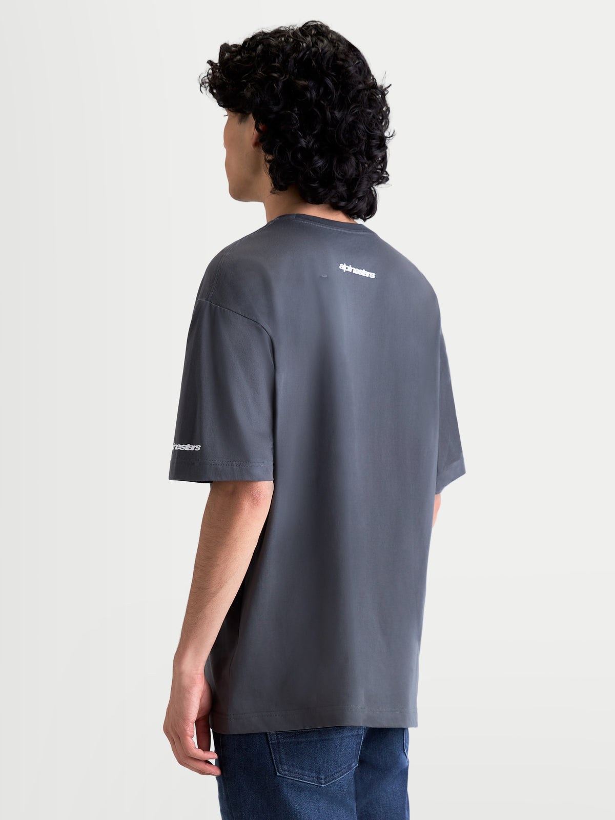 Alpinestars Mandate Oversized CSF T-shirt, mørkegrå kortærmet t-shirt med hvidt puff-print logo på ryggen og ærmet, oversized pasform, set bagfra på model, afslappet motorsport sportstøj