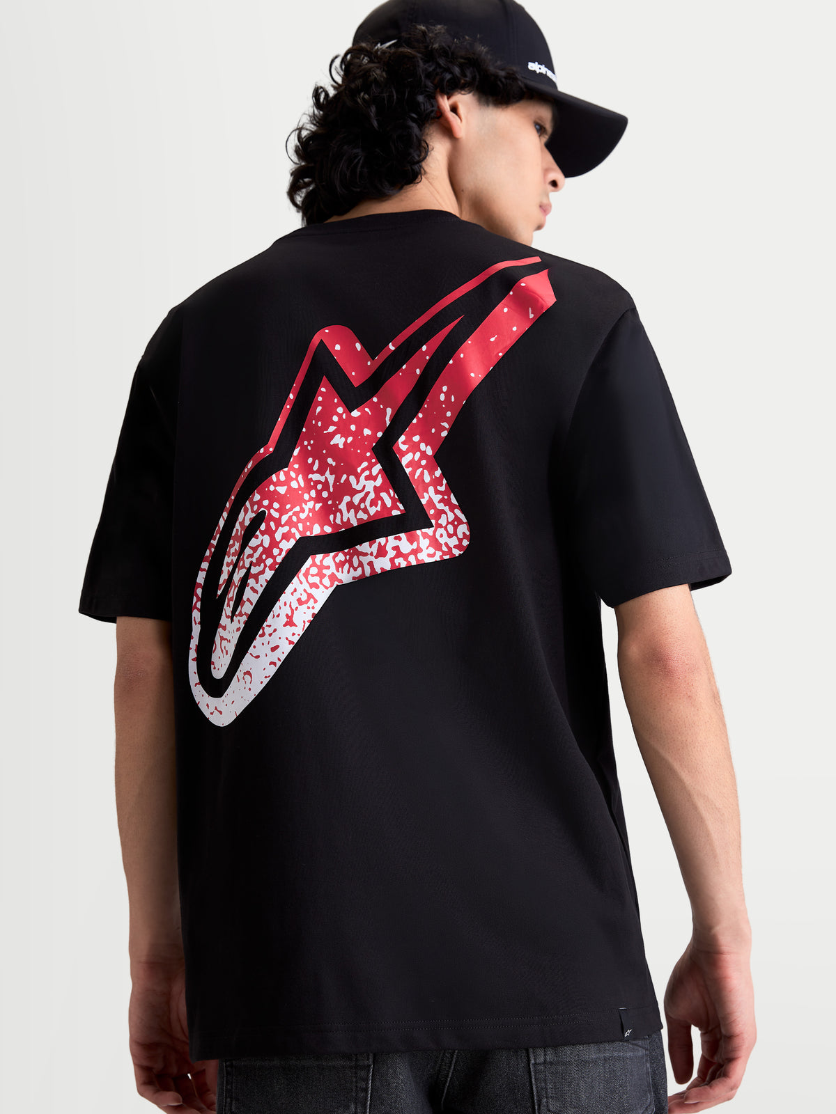 Alpinestars Meteor CSF T-shirt, sort kortærmet t-shirt set bagfra på model, stort rødt og hvidt MX-inspireret Astars-logo med farvegraduering, afslappet motorsport-sportswear.