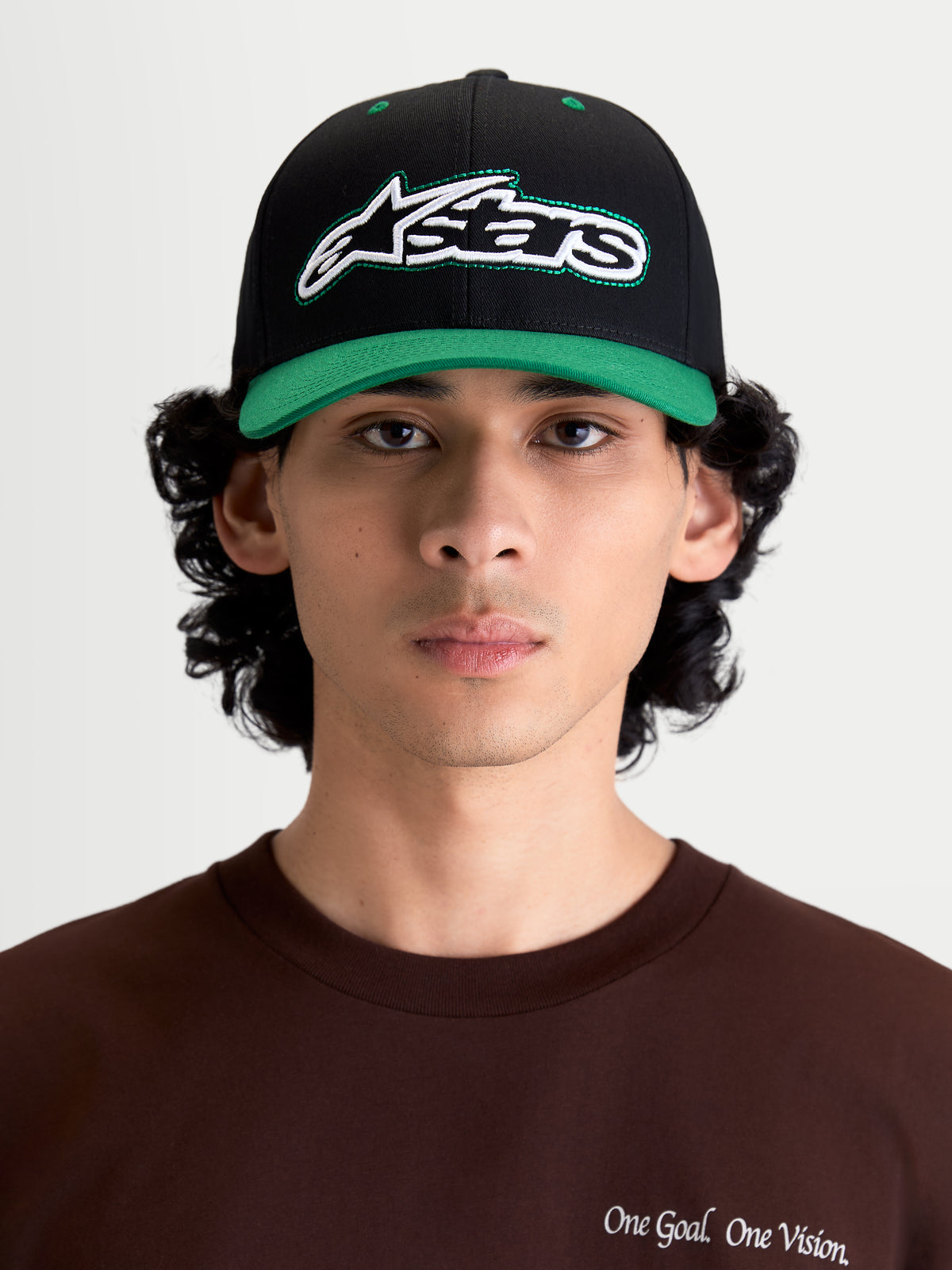 Alpinestars Retro Snapback kasket, sportswear livsstilskasket, sort og grøn, med buet skygge, struktureret krone og broderet Astars-logo med grønne løbesting, vist på model set forfra.