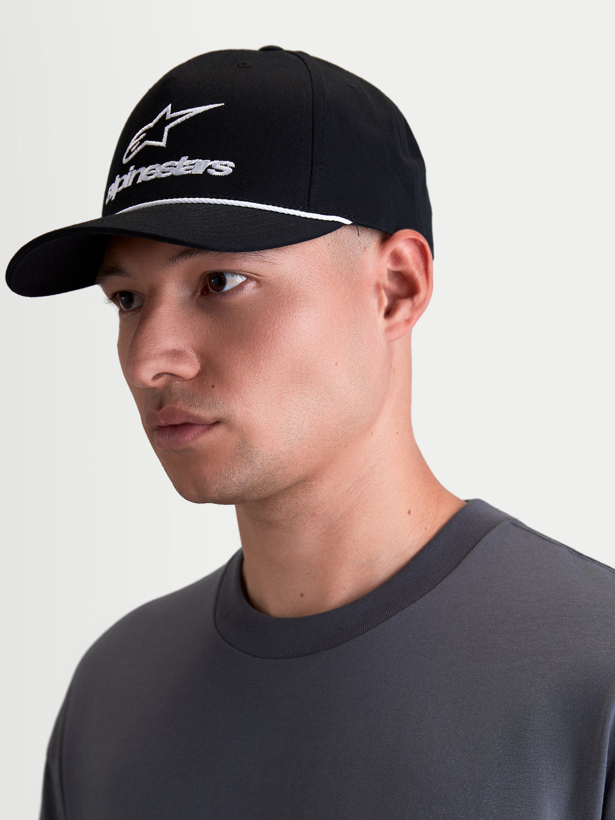 Alpinestars Combo Logo Snapback Kasket, sort og hvid sportswear-kasket med buet skygge, struktureret krone, hvidt broderet Alpinestars combo-logo og hvid snordetalje, vist på model i profil.